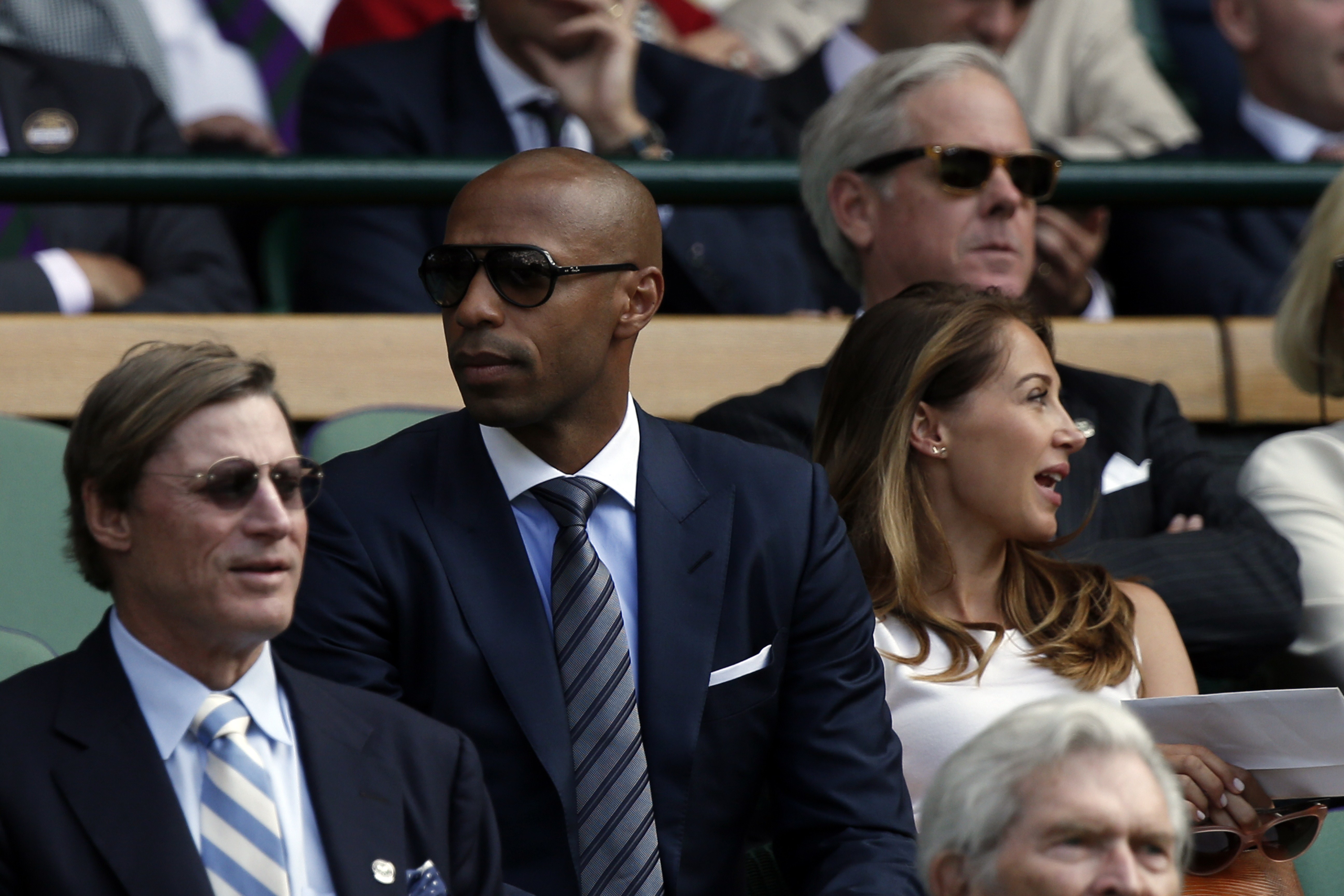 former French international football play Thierry Henry (C) sits with Andrea Rajacic, his pregnant girlfriend, on Centre Court as they watch Switzerland's Roger Federer play his men's semi-final match against  Britain's Andy Murray on day eleven of the 2015 Wimbledon Championships at The All England Tennis Club in Wimbledon, southwest London, on July 10, 2015.   RESTRICTED TO EDITORIAL USE  --  AFP PHOTO / ADRIAN DENNIS        (Photo credit should read ADRIAN DENNIS/AFP/Getty Images)