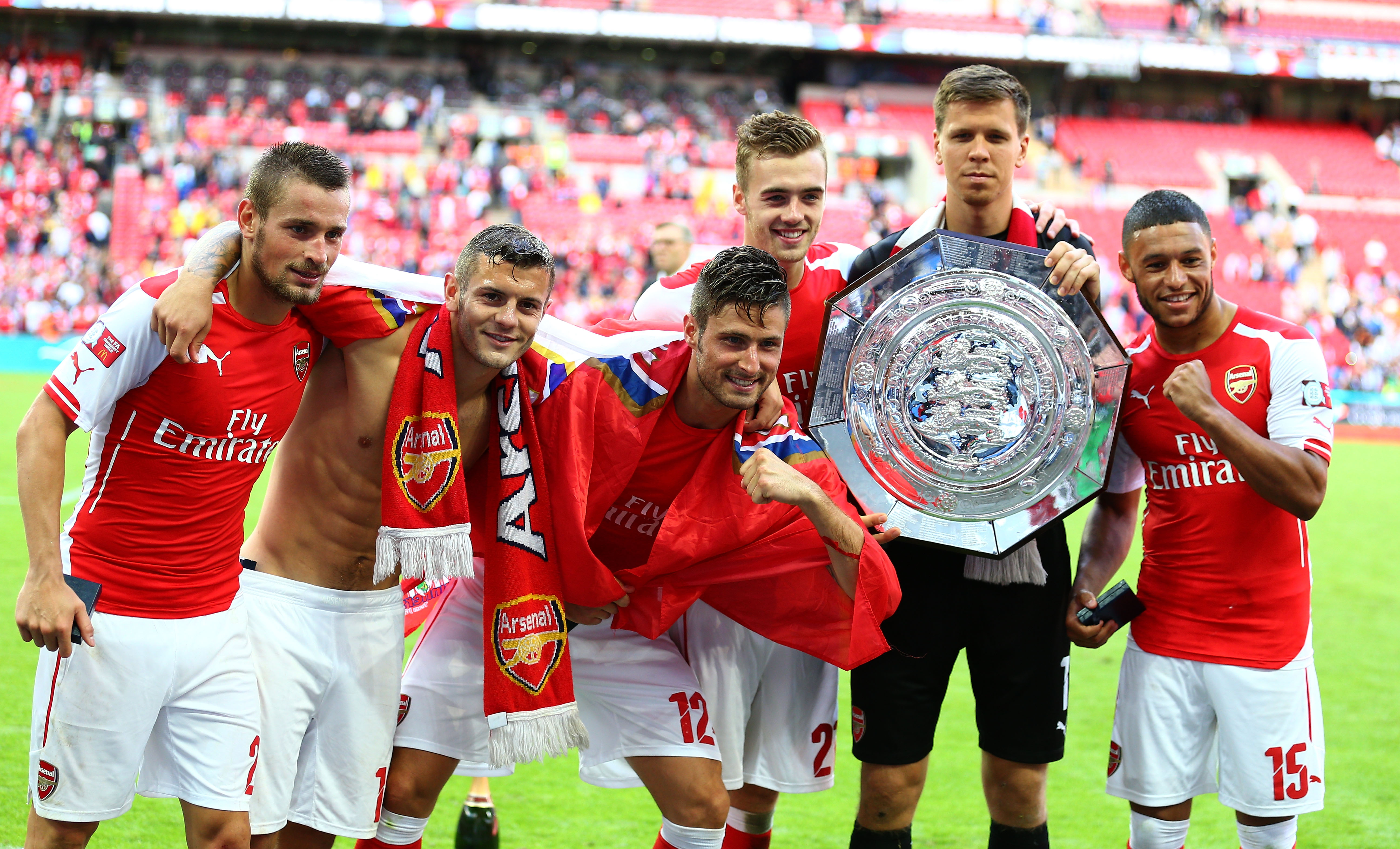 LONDON, ENGLAND - AUGUST 10:  Wojciech Szczesny of Arsenal holds the trophy as he poses with team-mates (L-R) Mathieu Debuchy, Jack Wilshere, Olivier Giroud, Calum Chambers and Alex Oxlade-Chamberlain after the FA Community Shield match between Manchester City and Arsenal at Wembley Stadium on August 10, 2014 in London, England.  (Photo by Clive Mason/Getty Images)