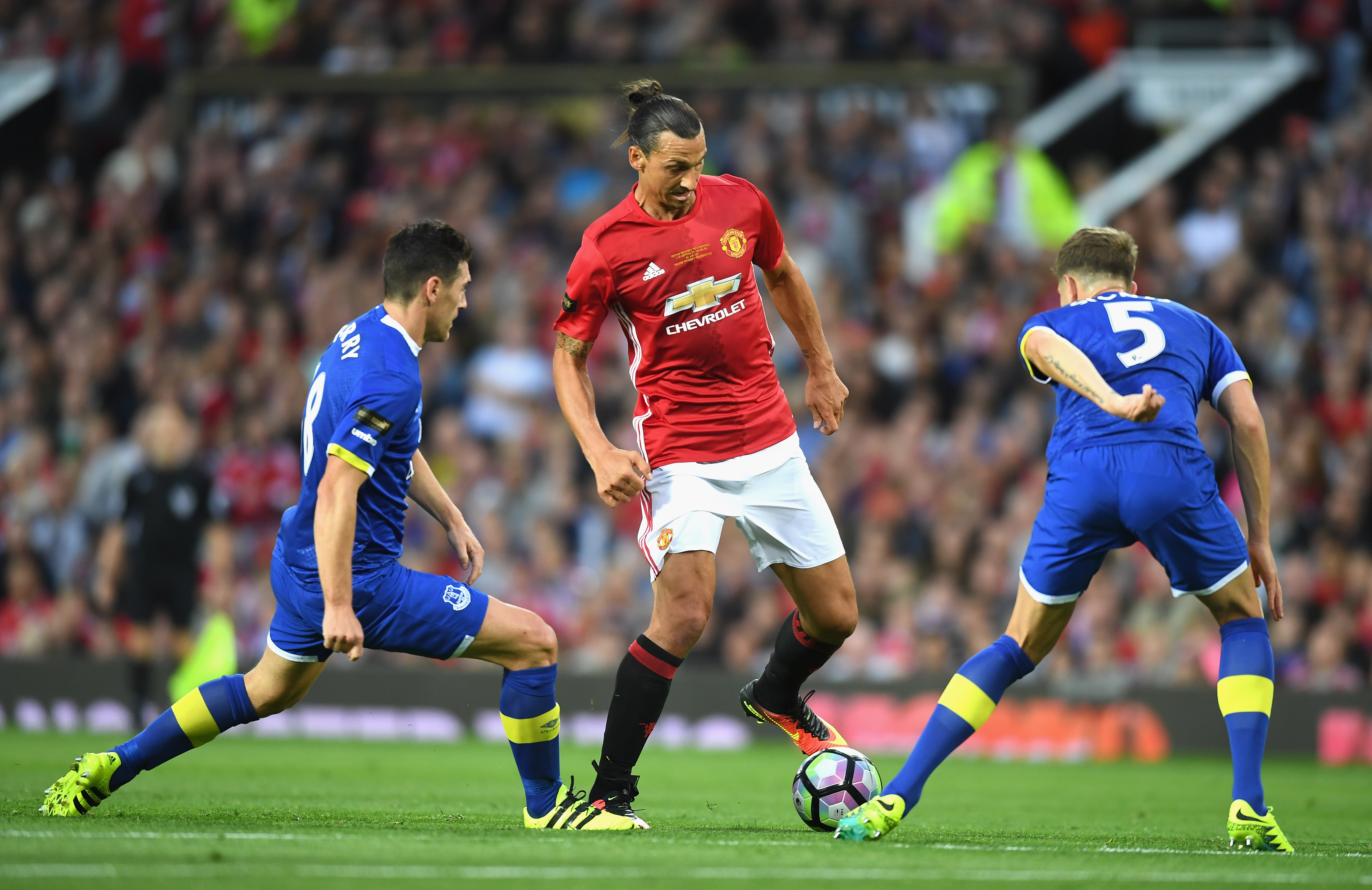 MANCHESTER, ENGLAND - AUGUST 03: Zlatan Ibrahimovic of Manchester United takes on John Stones and Gareth Barry of Everton during the Wayne Rooney Testimonial match between Manchester United and Everton at Old Trafford on August 3, 2016 in Manchester, England.  (Photo by Michael Regan/Getty Images)