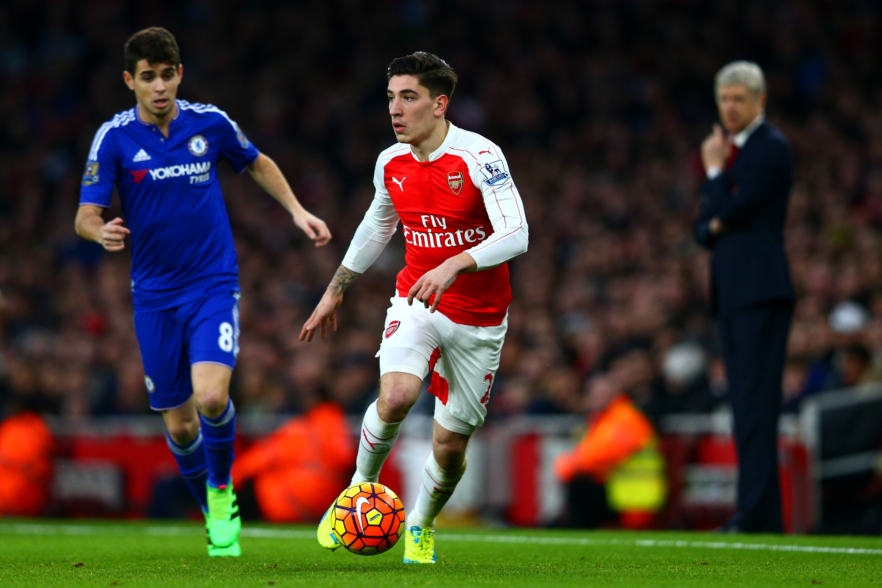 LONDON, ENGLAND - JANUARY 24:  Hector Bellerin of Arsenal runs with the ball under pressure from Oscar of Chelsea as Arsene Wenger, Manager of Arsenal looks on during the Barclays Premier League match between Arsenal and Chelsea at Emirates Stadium on January 24, 2016 in London, England.  (Photo by Clive Mason/Getty Images)