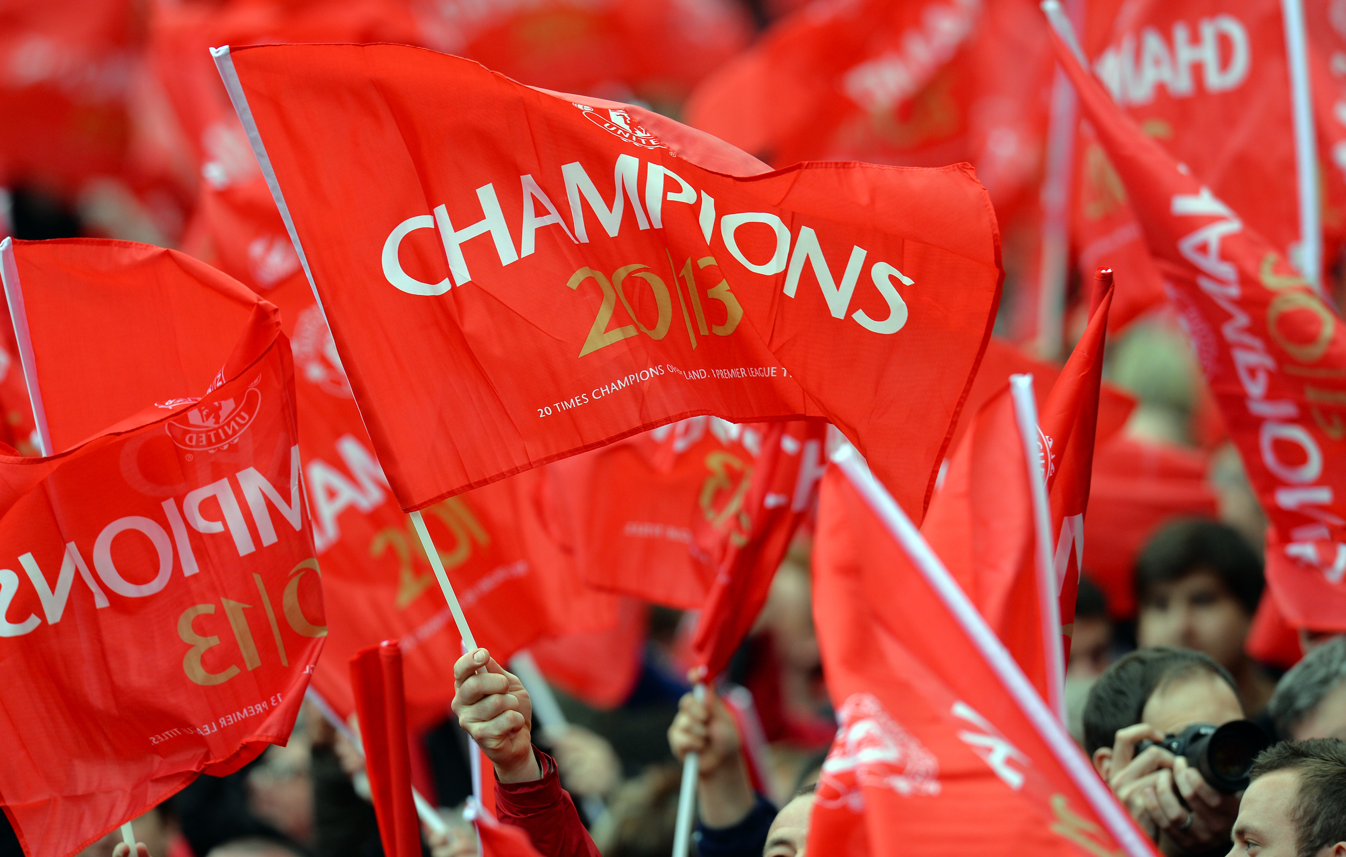 Supports hold red 'champions' flags during the English Premier League football match between Manchester United and Swansea City at Old Trafford in Manchester, northwest England, on May 12, 2013.  (Photo by Andrew Yates/AFP/Getty Images)