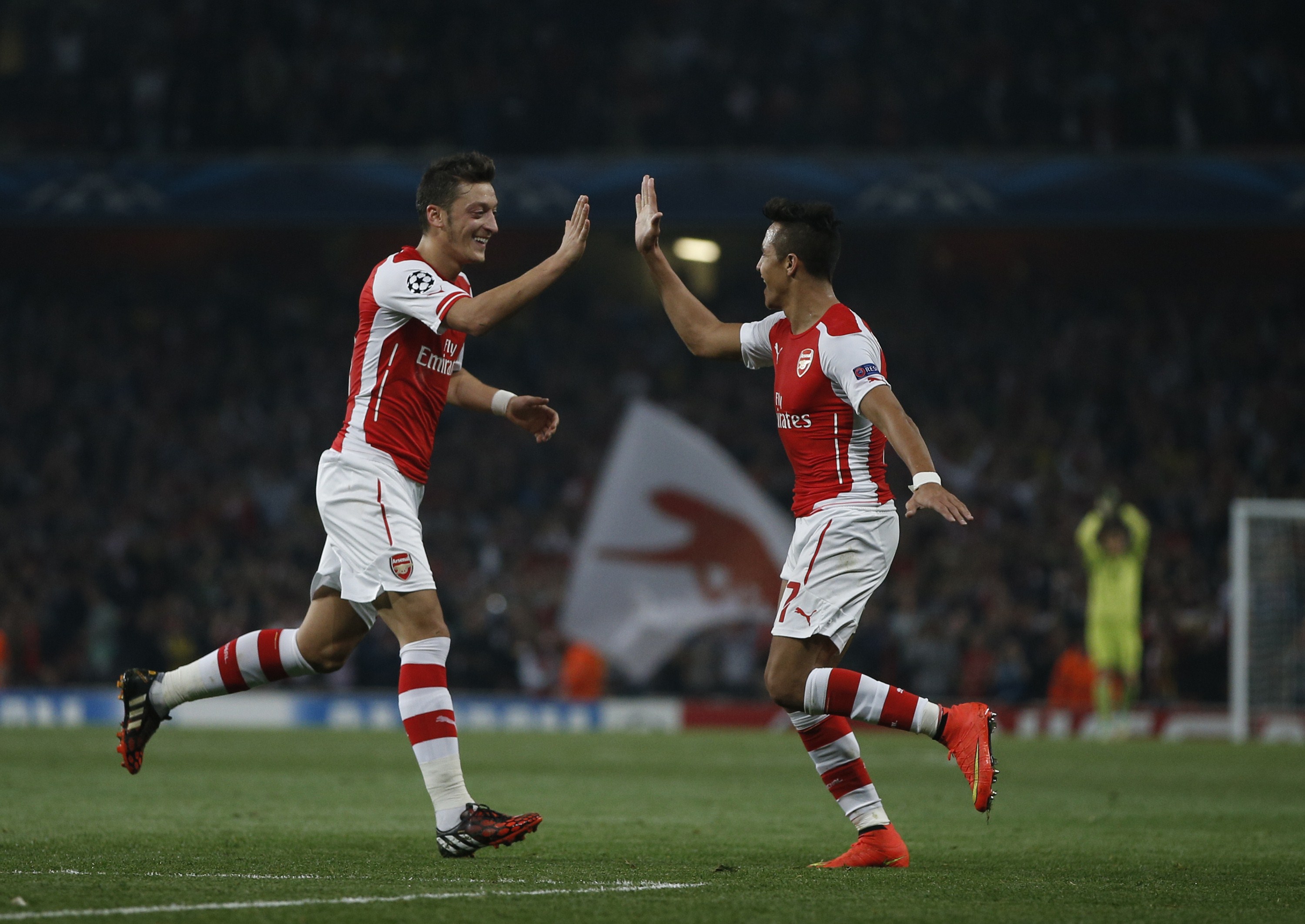 Arsenal's Chilean striker Alexis Sanchez (R) celebrates scoring his goal with Arsenal's German midfielder Mesut Ozil (L) during the UEFA Champions League, Group D football match between Arsenal and Galatasaray at The Emirates Stadium in north London on October 1, 2014. Arsenal won the game 4-1. (Photo by Adrian Dennis/AFP/Getty Images)