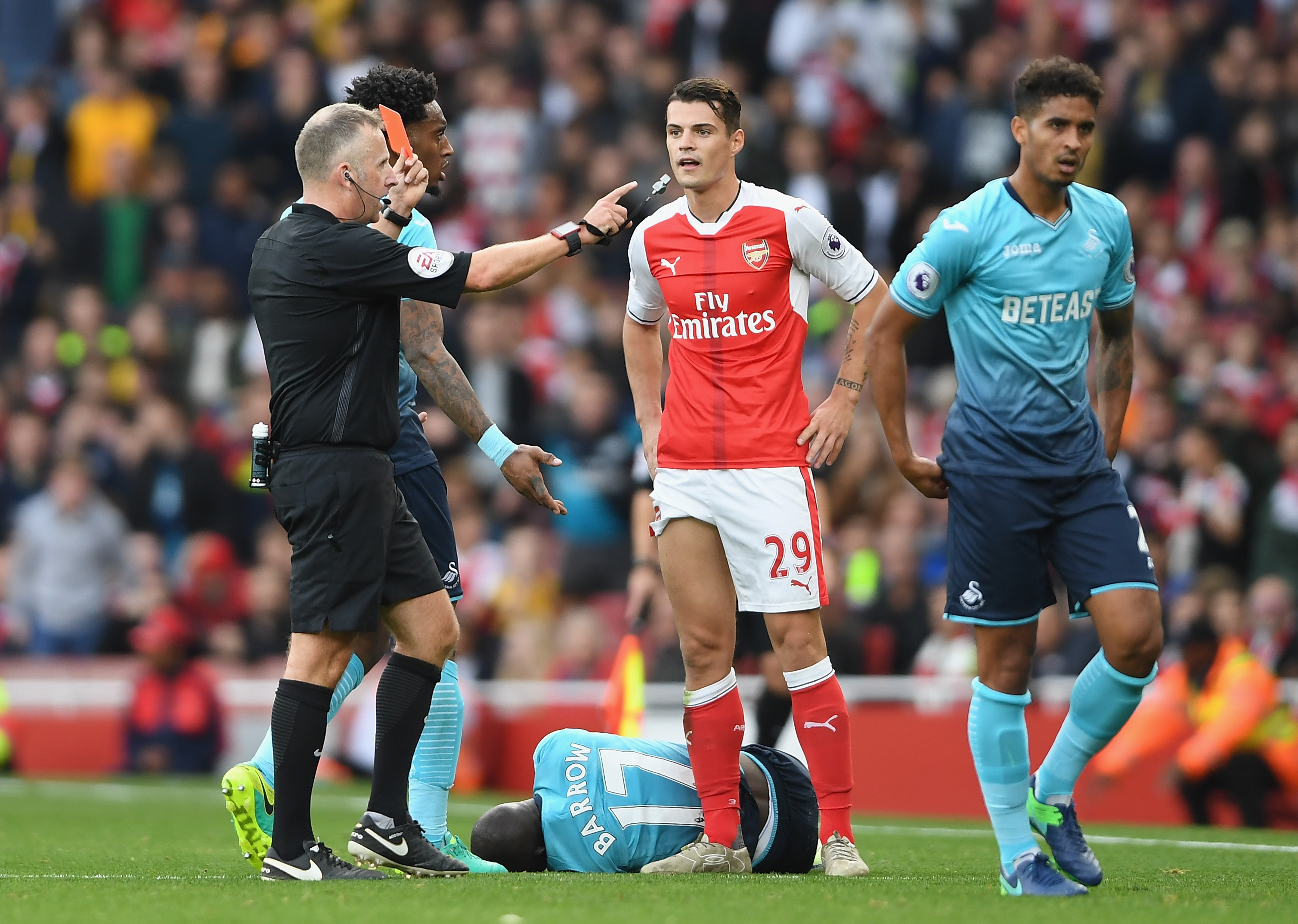 LONDON, ENGLAND - OCTOBER 15: Referee Jonanthan Moss (L) shows Granit Xhaka of Arsenal (C) a red card for a foul on Modou Barrow of Swansea City during the Premier League match between Arsenal and Swansea City at Emirates Stadium on October 15, 2016 in London, England.  (Photo by Mike Hewitt/Getty Images)