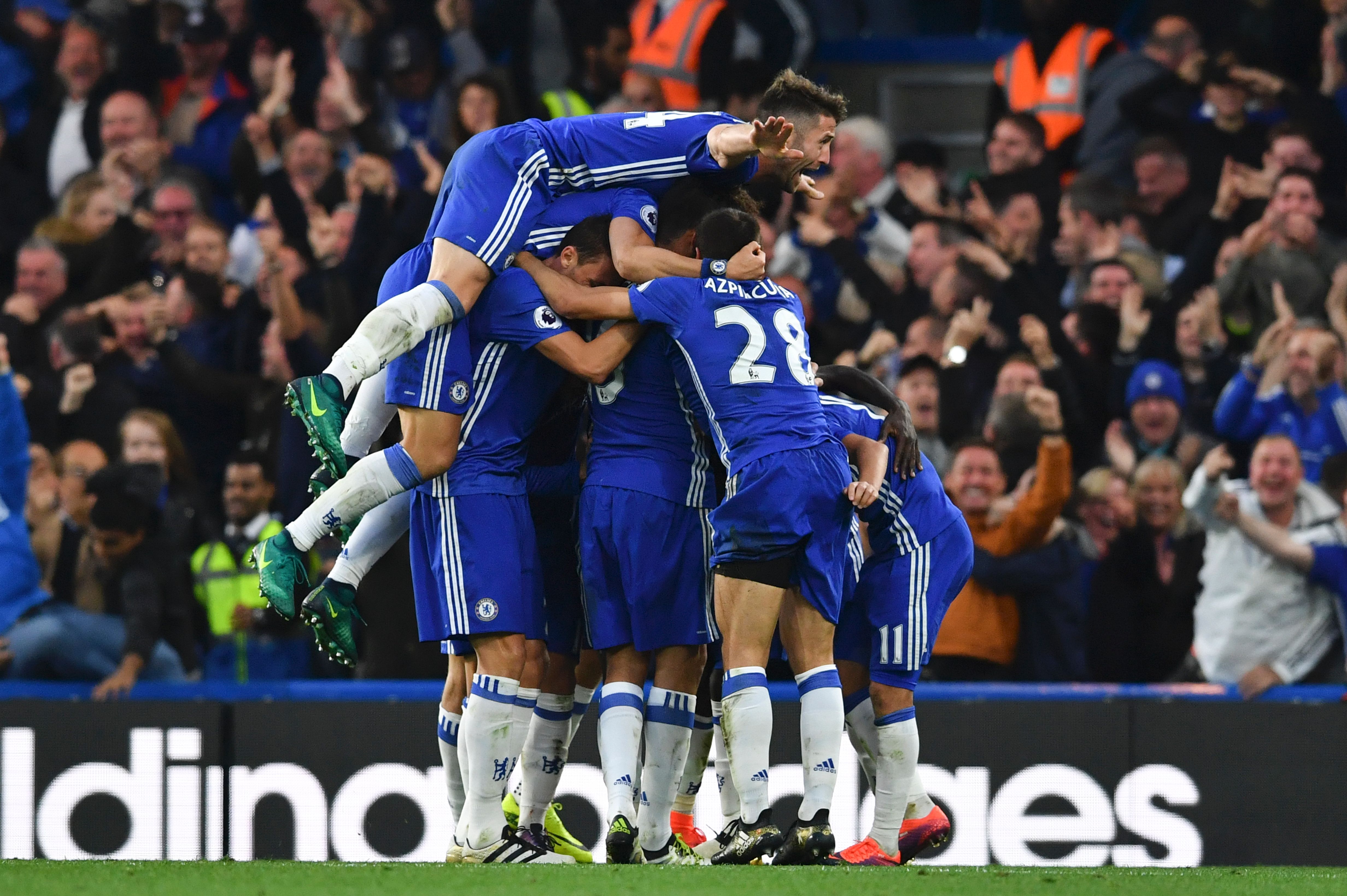 Chelsea's English defender Gary Cahill (top) jumps onto the huddle to join the celebrates after Chelsea's French midfielder N'Golo Kante scored their fourth goal during the English Premier League football match between Chelsea and Manchester United at Stamford Bridge in London on October 23, 2016. / AFP / BEN STANSALL / RESTRICTED TO EDITORIAL USE. No use with unauthorized audio, video, data, fixture lists, club/league logos or 'live' services. Online in-match use limited to 75 images, no video emulation. No use in betting, games or single club/league/player publications.  /         (Photo credit should read BEN STANSALL/AFP/Getty Images)