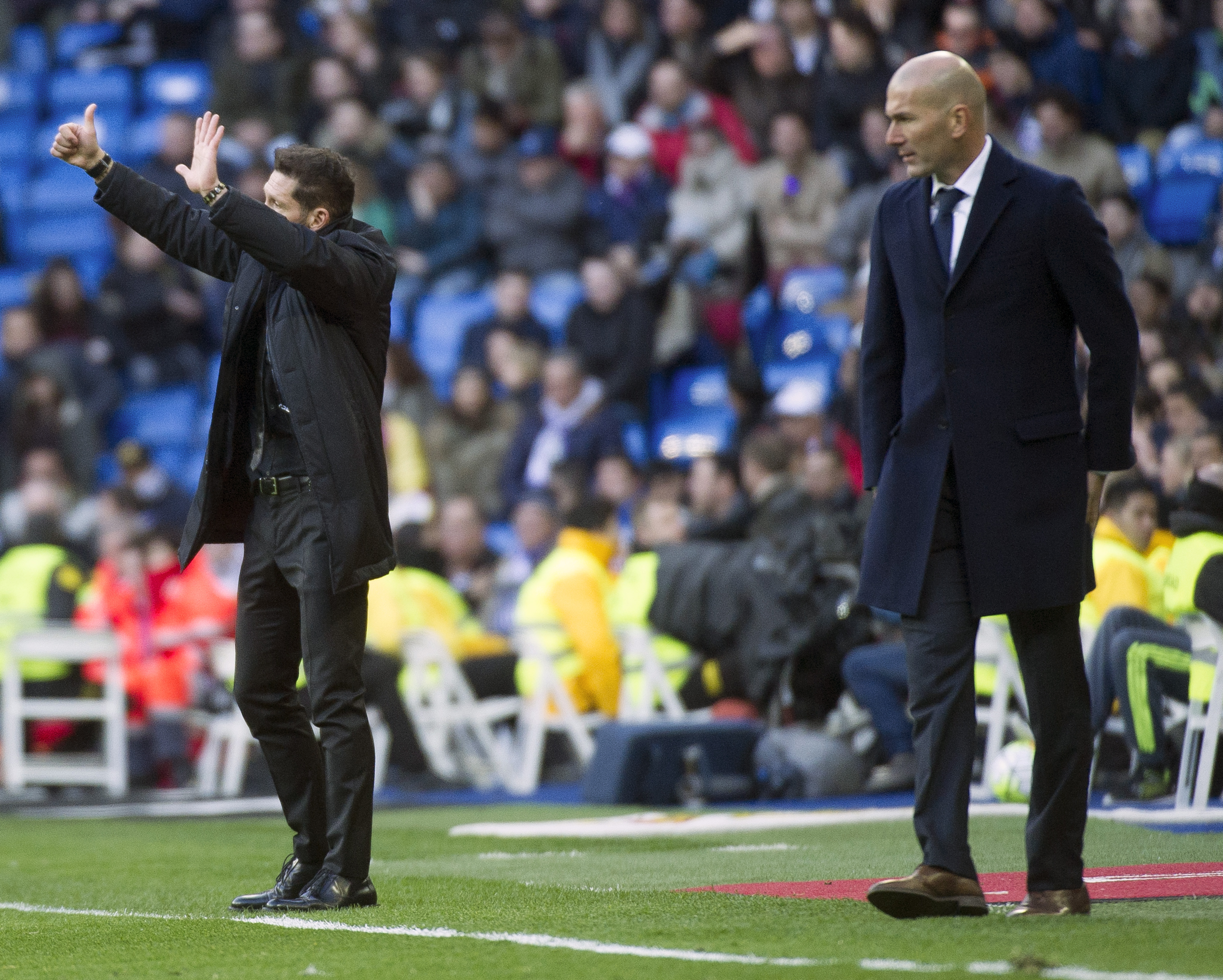 Atletico Madrid's Argentinian coach Diego Simeone (L) gestures next to Real Madrid's French coach Zinedine Zidane during the Spanish league football match Real Madrid CF vs Club Atletico de Madrid at the Santiago Bernabeu stadium in Madrid on February 27, 2016. / AFP / CURTO DE LA TORRE        (Photo credit should read CURTO DE LA TORRE/AFP/Getty Images)