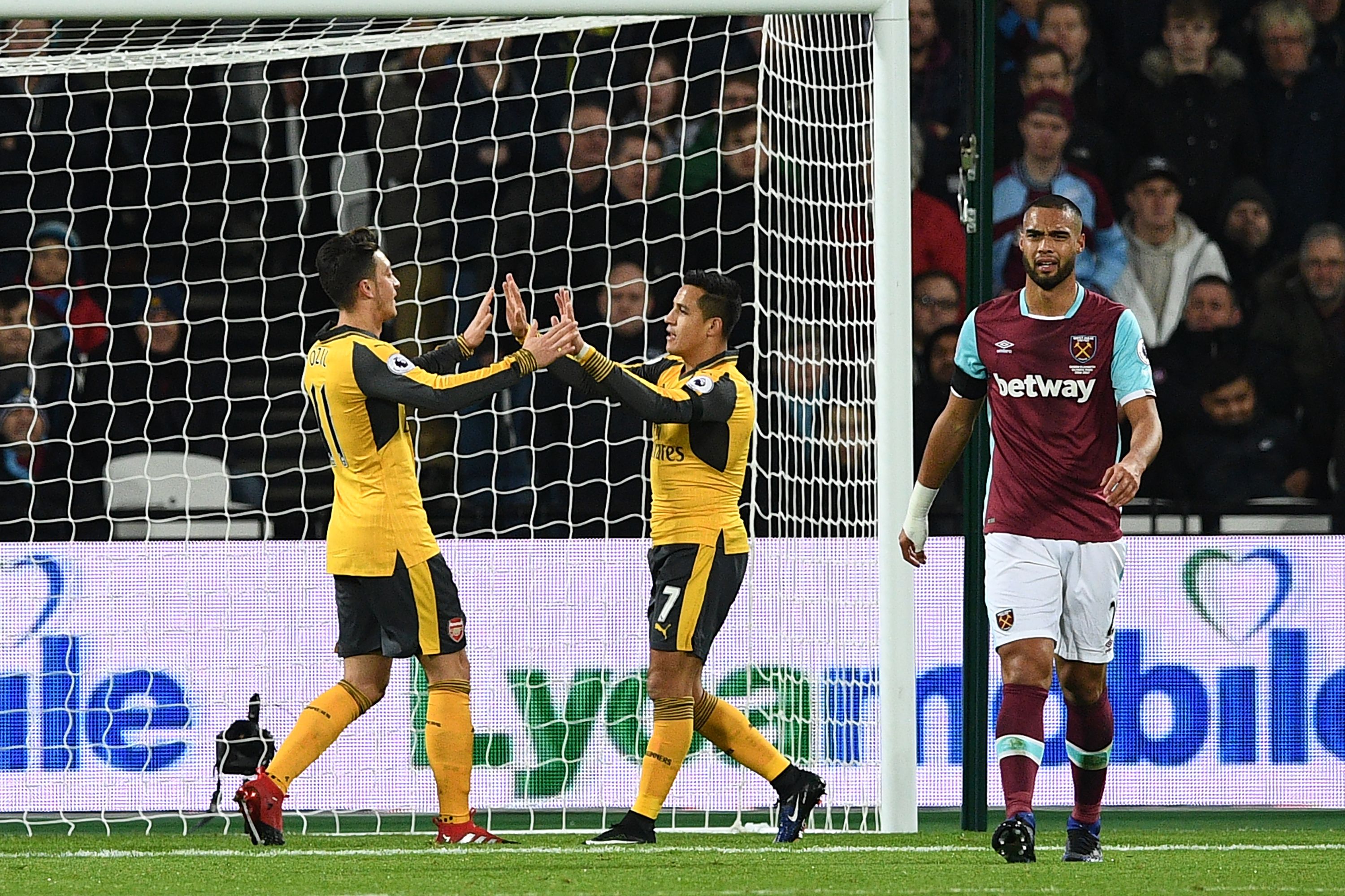 Arsenal's German midfielder Mesut Ozil (L) celebrates with Arsenal's Chilean striker Alexis Sanchez after scoring the opening goal of the English Premier League football match between West Ham United and Arsenal at The London Stadium, in east London on December 3, 2016. / AFP / Justin TALLIS / RESTRICTED TO EDITORIAL USE. No use with unauthorized audio, video, data, fixture lists, club/league logos or 'live' services. Online in-match use limited to 75 images, no video emulation. No use in betting, games or single club/league/player publications.  /         (Photo credit should read JUSTIN TALLIS/AFP/Getty Images)