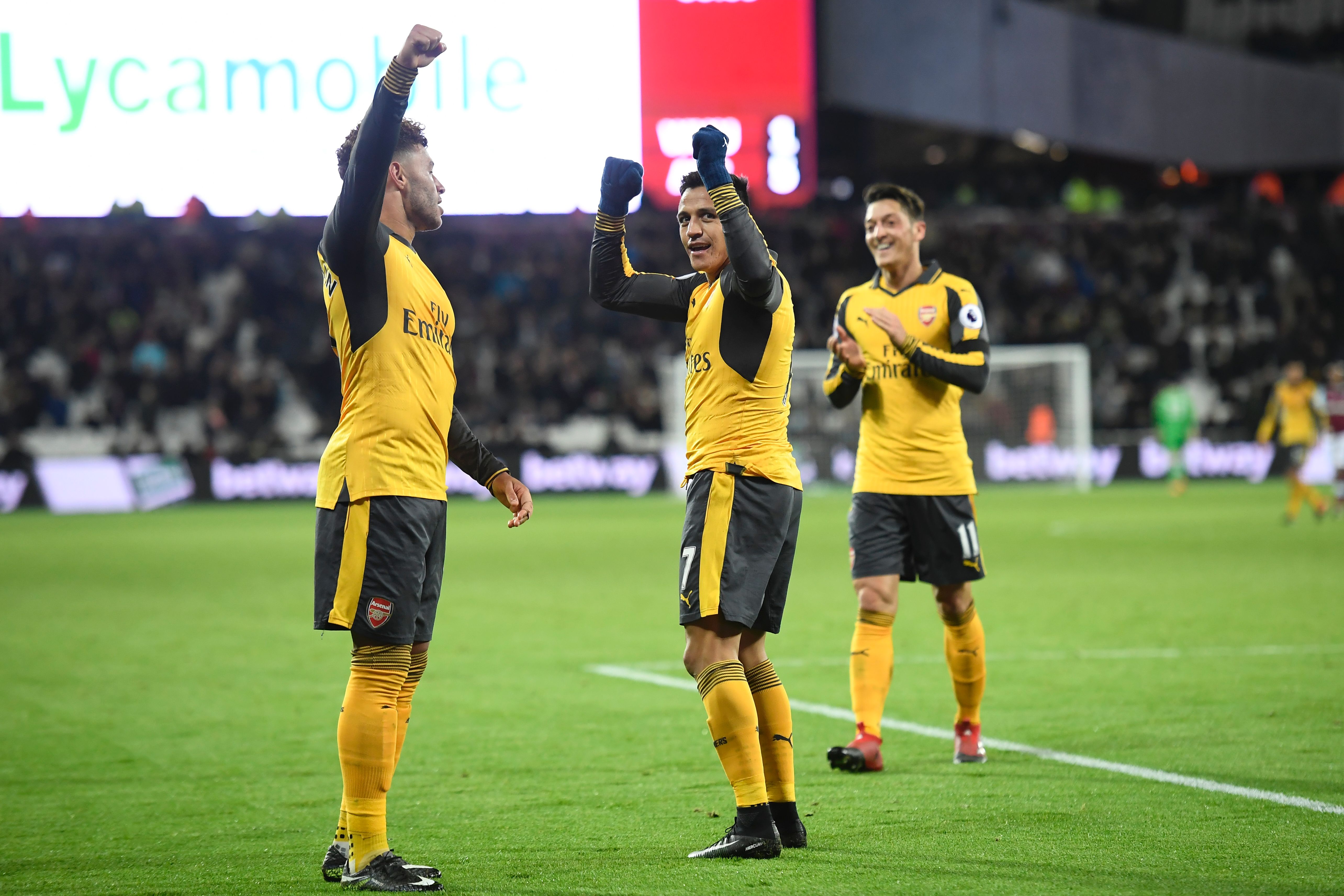 The three goal-scorers, Arsenal's English midfielder Alex Oxlade-Chamberlain (L), Arsenal's Chilean striker Alexis Sanchez (C) and Arsenal's German midfielder Mesut Ozil (R) celebrate Sanchez's third goal, the team's fifth, during the English Premier League football match between West Ham United and Arsenal at The London Stadium, in east London on December 3, 2016.
Arsenal won the game 5-1. / AFP / Justin TALLIS / RESTRICTED TO EDITORIAL USE. No use with unauthorized audio, video, data, fixture lists, club/league logos or 'live' services. Online in-match use limited to 75 images, no video emulation. No use in betting, games or single club/league/player publications.  /         (Photo credit should read JUSTIN TALLIS/AFP/Getty Images)
