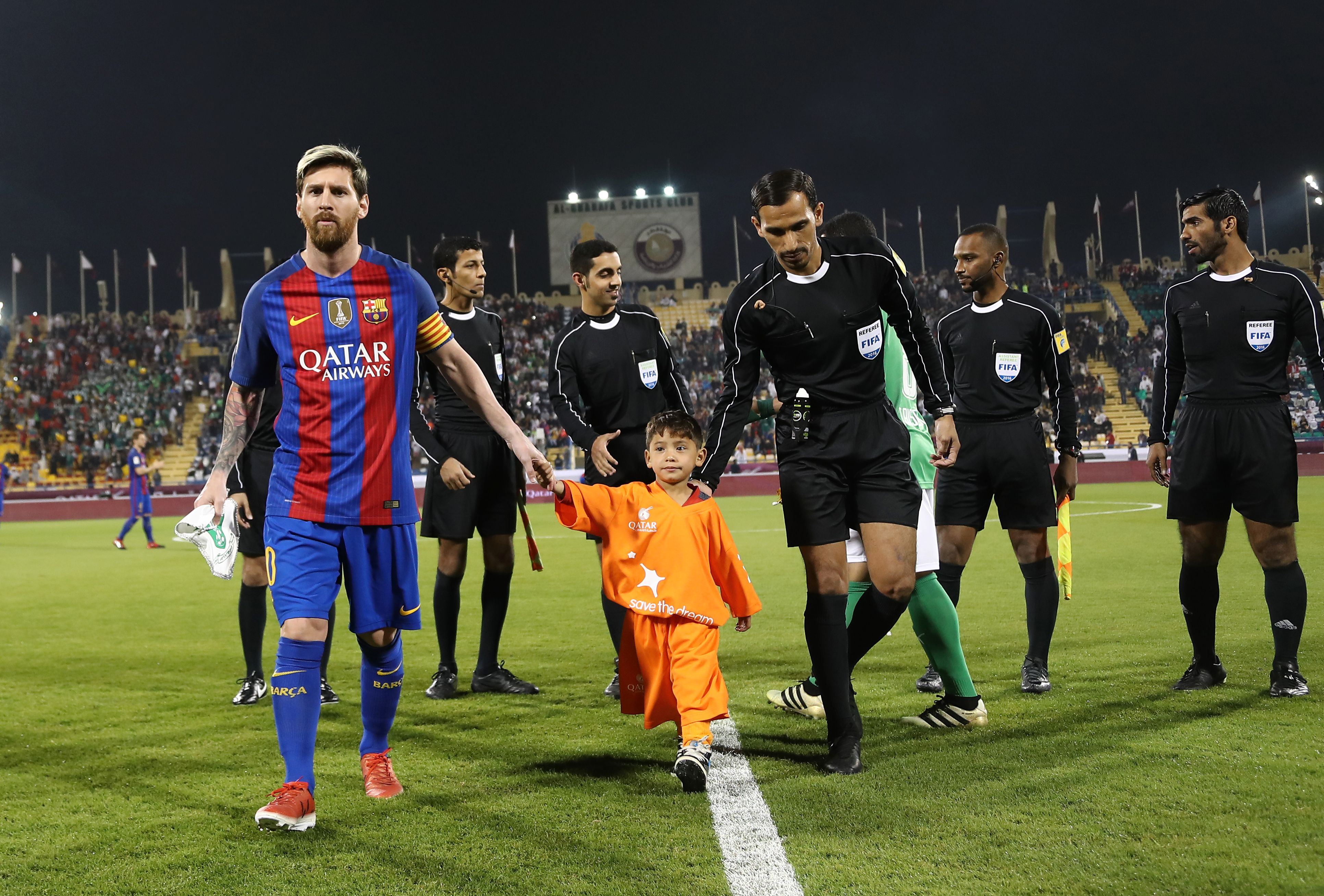 FC Barcelona Lionel Messi (L) holds the hands of Afghan boy Murtaza Ahmadi on the pitch before the start of a friendly football match against Saudi Arabia's Al-Ahli FC on December 13, 2016 in the Qatari capital Doha. 
Barcelona play Saudi champions Al-Ahli in a friendly in Doha, the Spanish club's last major obligation of its four year shirt sponsorship deal with Qatar Airways.

 / AFP / KARIM JAAFAR        (Photo credit should read KARIM JAAFAR/AFP/Getty Images)