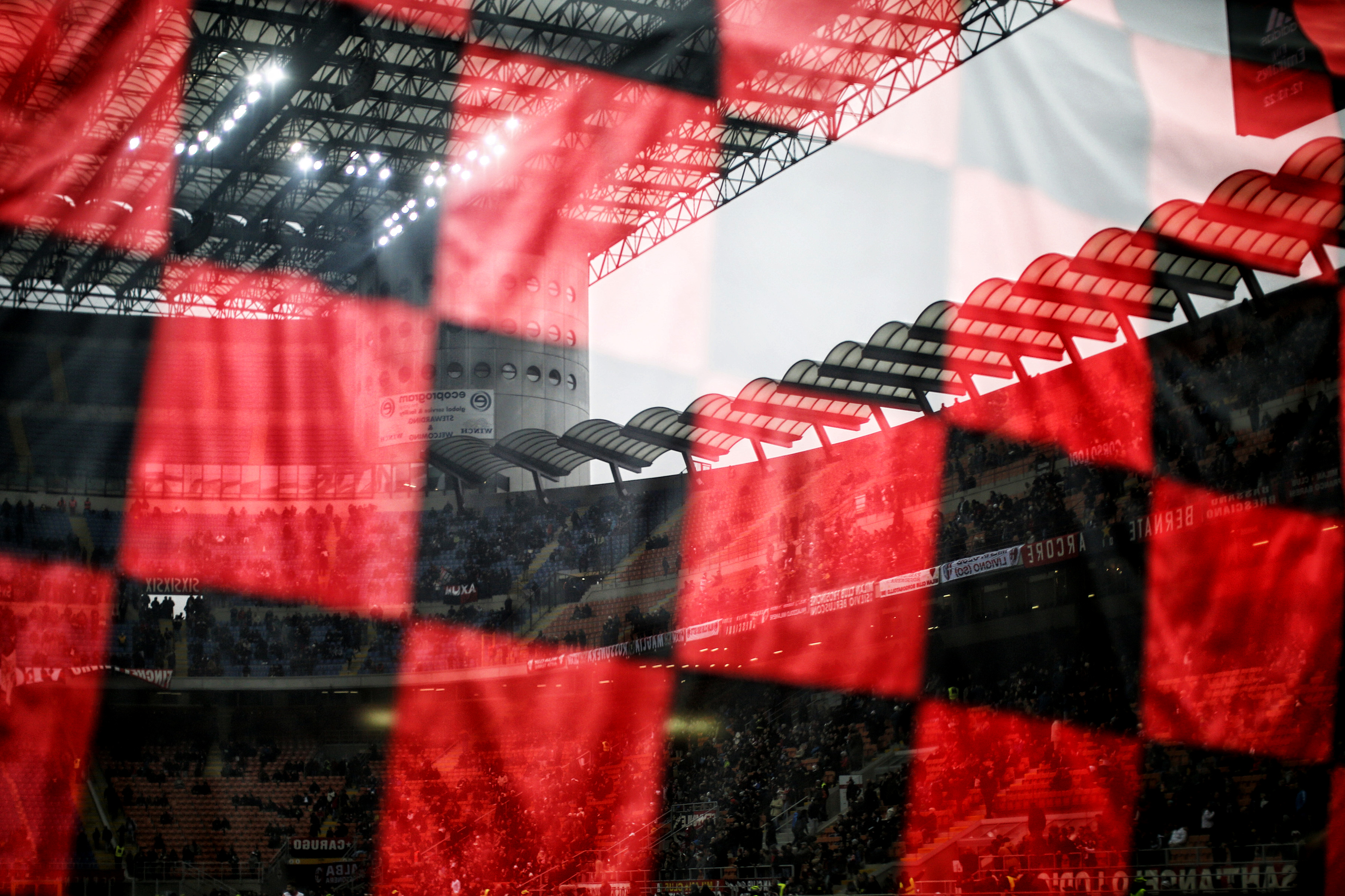 The stands of the San Siro stadium reflect in a window with a flag of AC Milang during the Italian Serie A football match AC Milan Vs Crotone on December 4, 2016 at the 'San Siro Stadium' in Milan.  / AFP / MARCO BERTORELLO        (Photo credit should read MARCO BERTORELLO/AFP/Getty Images)