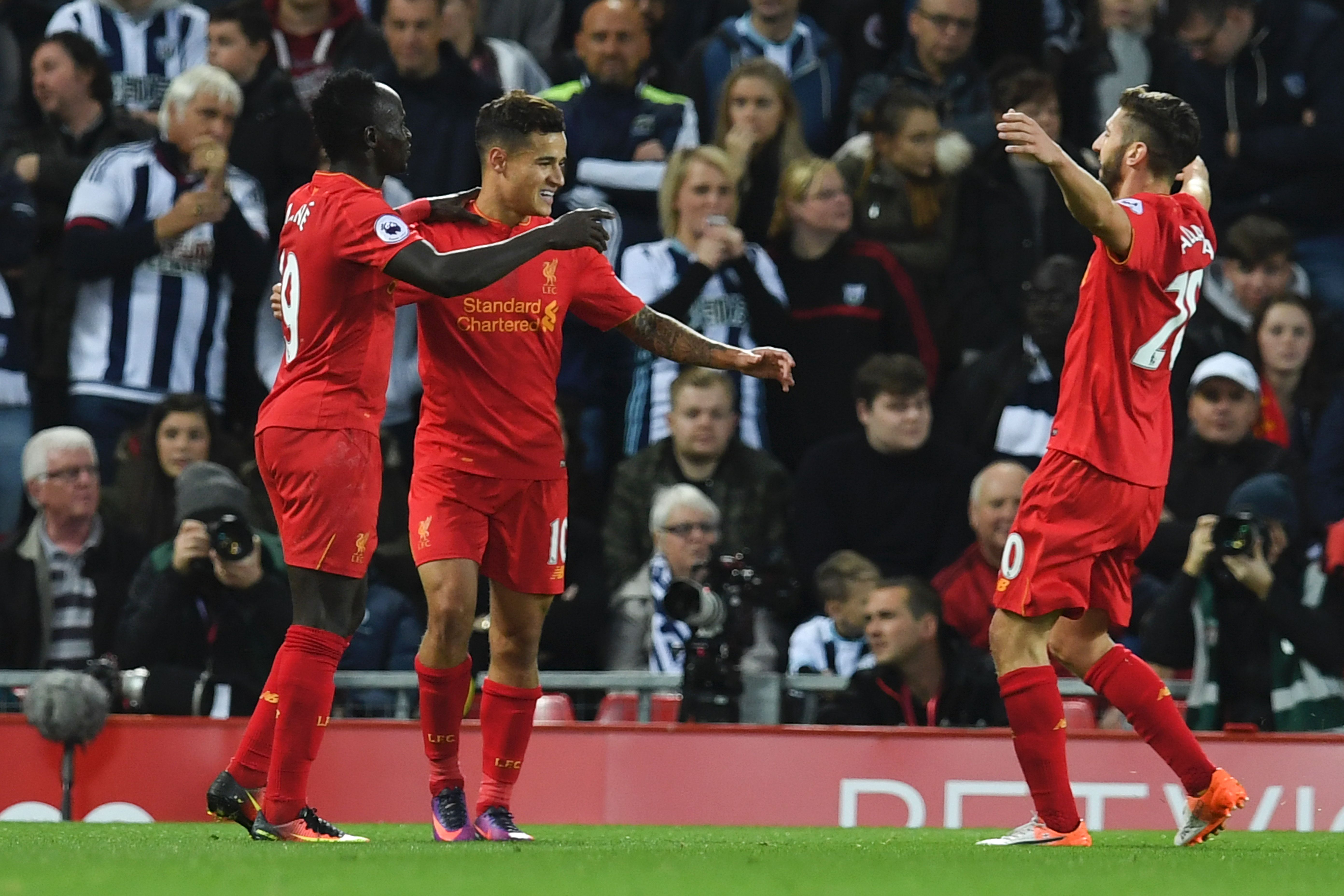 Liverpool's Brazilian midfielder Philippe Coutinho (C) celebrates scoring their second goal with Liverpool's Senegalese midfielder Sadio Mane (L) and Liverpool's English midfielder Adam Lallana (R) during the English Premier League football match between Liverpool and West Bromwich Albion at Anfield in Liverpool, north west England on October 22, 2016. / AFP / PAUL ELLIS / RESTRICTED TO EDITORIAL USE. No use with unauthorized audio, video, data, fixture lists, club/league logos or 'live' services. Online in-match use limited to 75 images, no video emulation. No use in betting, games or single club/league/player publications.  /         (Photo credit should read PAUL ELLIS/AFP/Getty Images)