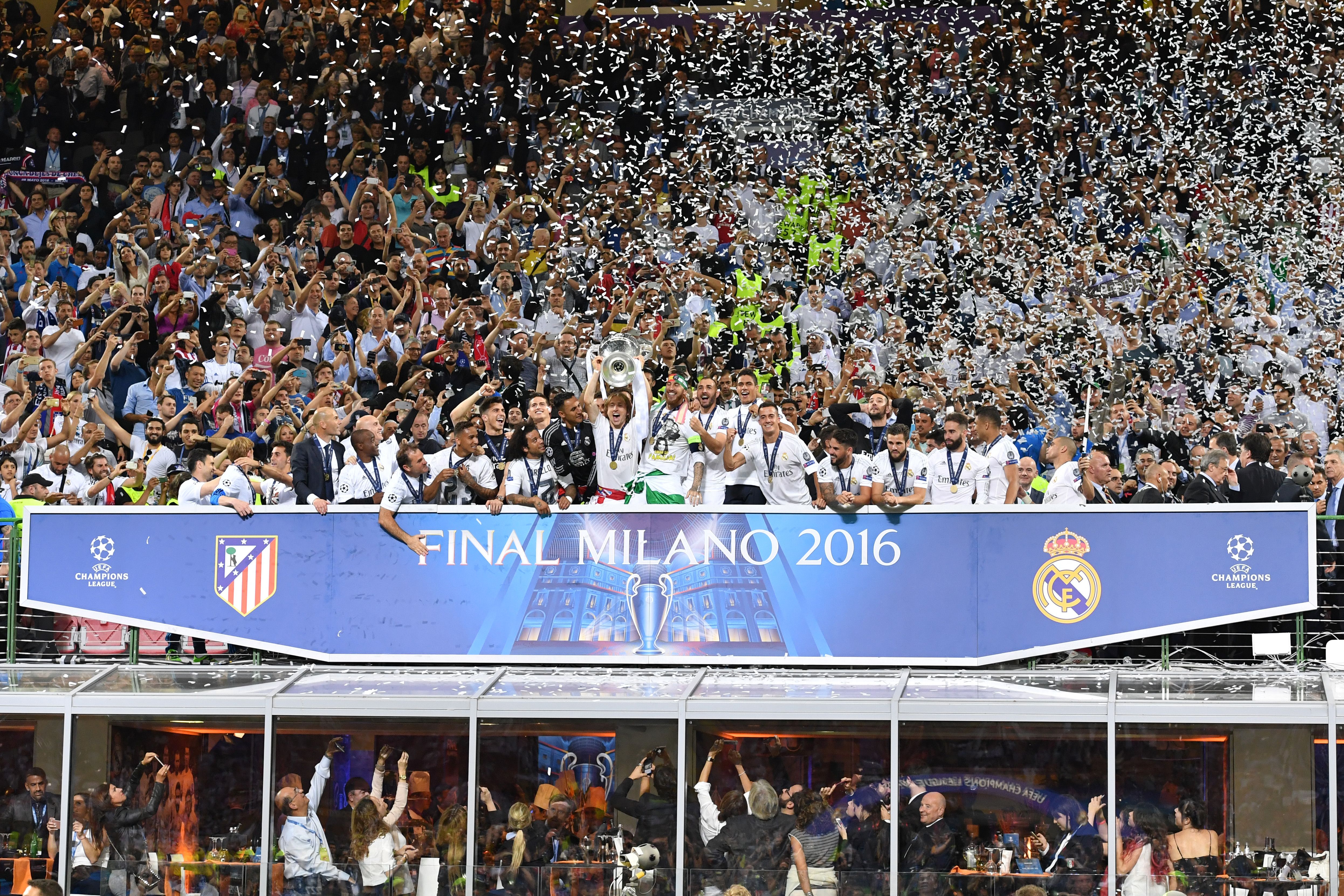 Real Madrid's Croatian midfielder Luka Modric (C) lifts the trophy as Real Madrid players celebrate winning the UEFA Champions League final football match over Atletico Madrid at San Siro Stadium in Milan, on May 28, 2016. / AFP / GERARD JULIEN        (Photo credit should read GERARD JULIEN/AFP/Getty Images)