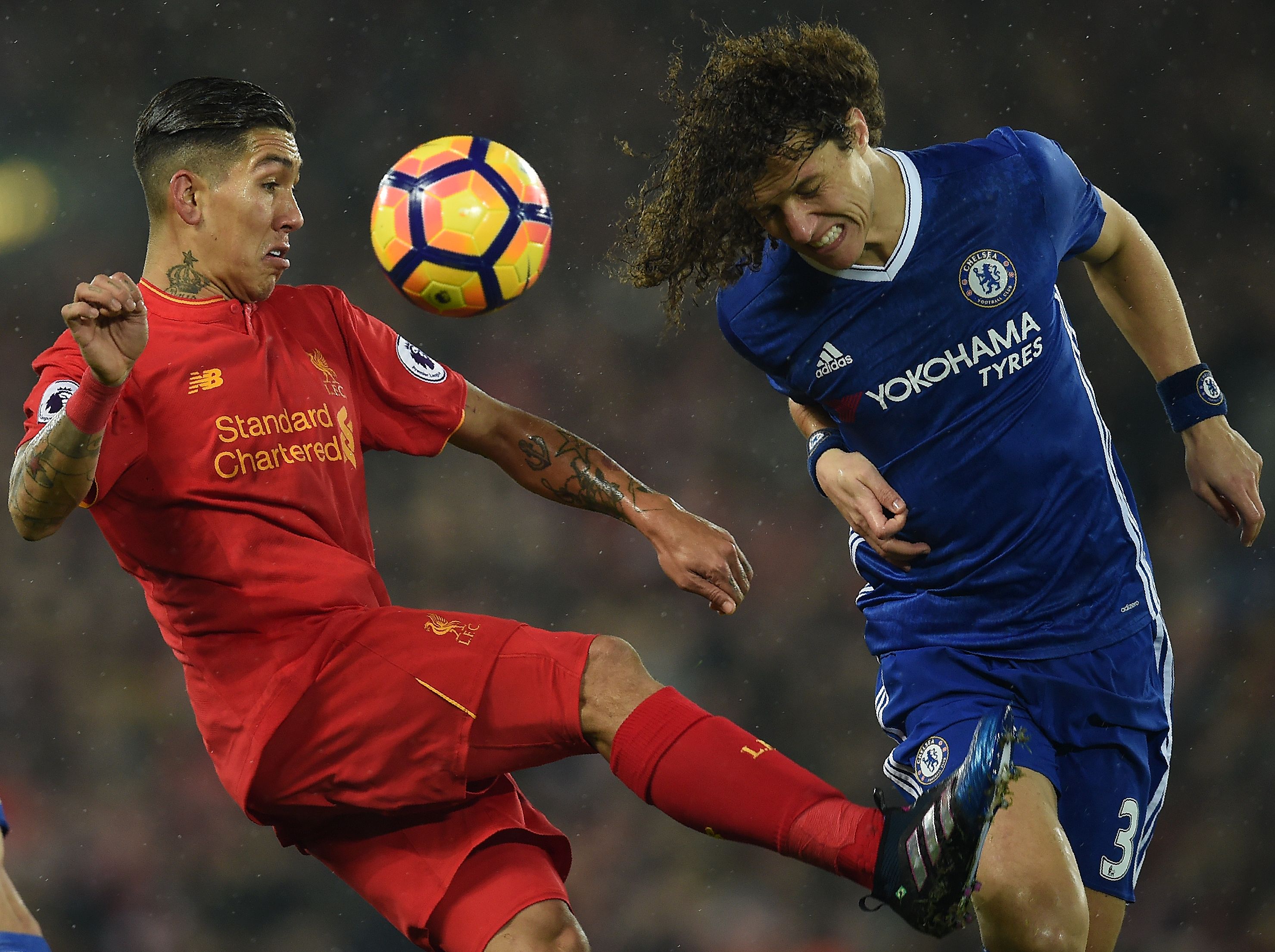 Liverpool's Brazilian midfielder Roberto Firmino (L) vies with Chelsea's Brazilian defender David Luiz during the English Premier League football match between Liverpool and Chelsea at Anfield in Liverpool, north west England on January 31, 2017. / AFP / PAUL ELLIS / RESTRICTED TO EDITORIAL USE. No use with unauthorized audio, video, data, fixture lists, club/league logos or 'live' services. Online in-match use limited to 75 images, no video emulation. No use in betting, games or single club/league/player publications.  /         (Photo credit should read PAUL ELLIS/AFP/Getty Images)