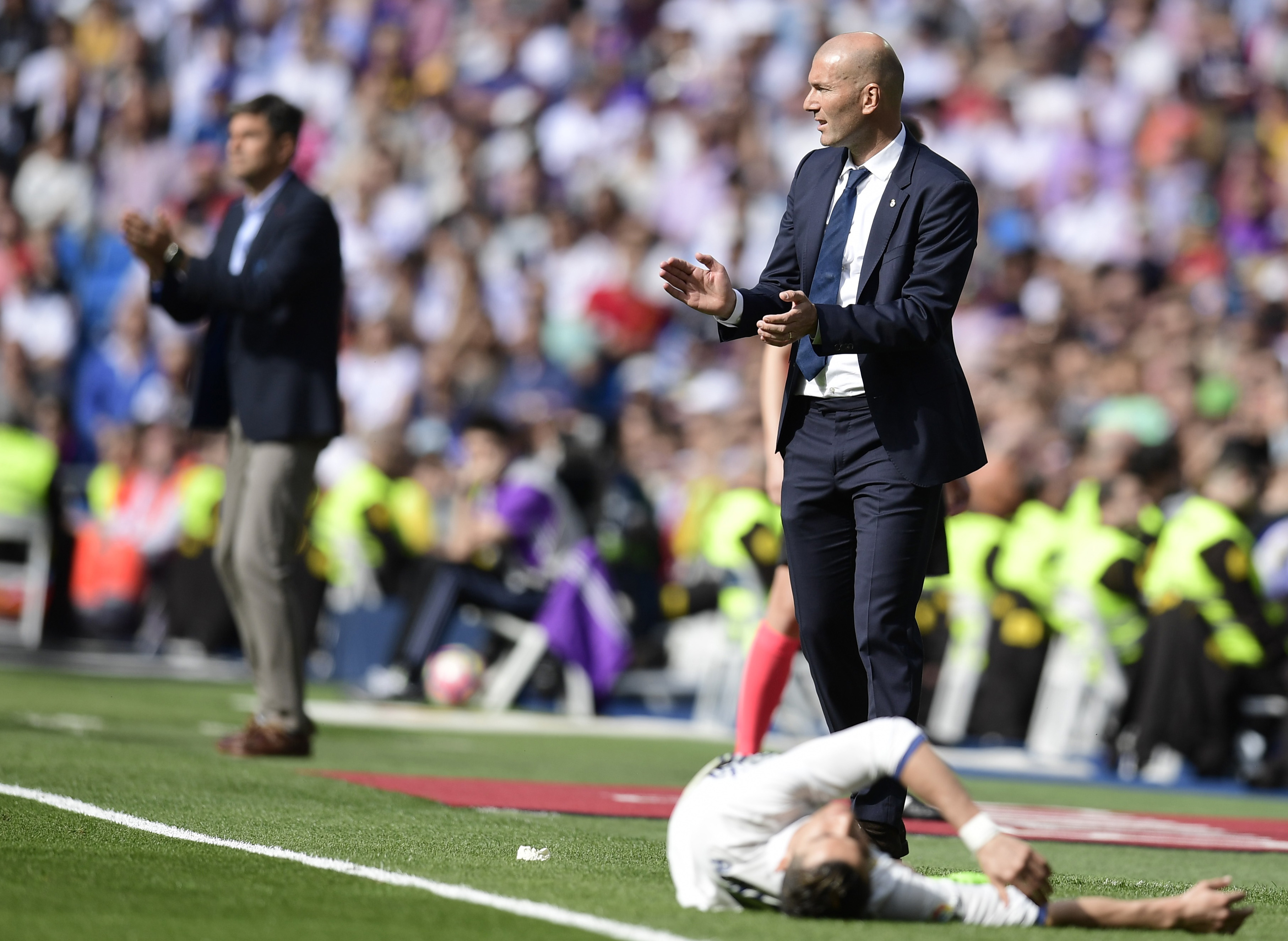 TOPSHOT - Real Madrid's French coach Zinedine Zidane (R) applauds as Real Madrid's Portuguese forward Cristiano Ronaldo lies in front of him during the Spanish league football match Real Madrid CF vs Deportivo Alaves at the Santiago Bernabeu stadium in Madrid on April 2, 2017. / AFP PHOTO / JAVIER SORIANO        (Photo credit should read JAVIER SORIANO/AFP/Getty Images)