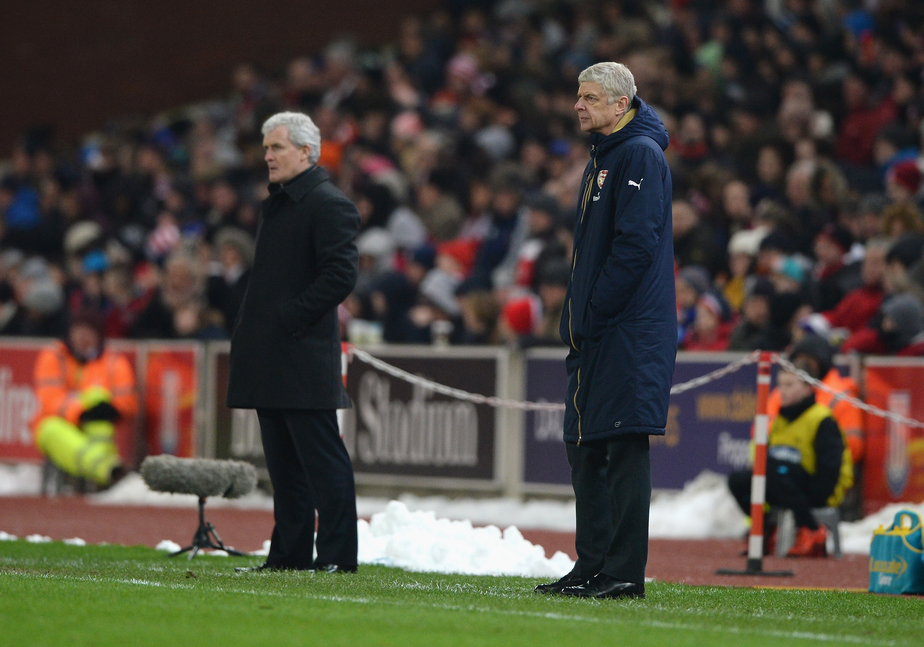 STOKE ON TRENT, ENGLAND - JANUARY 17:  Arsene Wenger, manager of Arsenal looks on with Mark Hughes, manager of Stoke City during the Barclays Premier League match between Stoke City and Arsenal at Britannia Stadium on January 17, 2016 in Stoke on Trent, England.  (Photo by Gareth Copley/Getty Images)