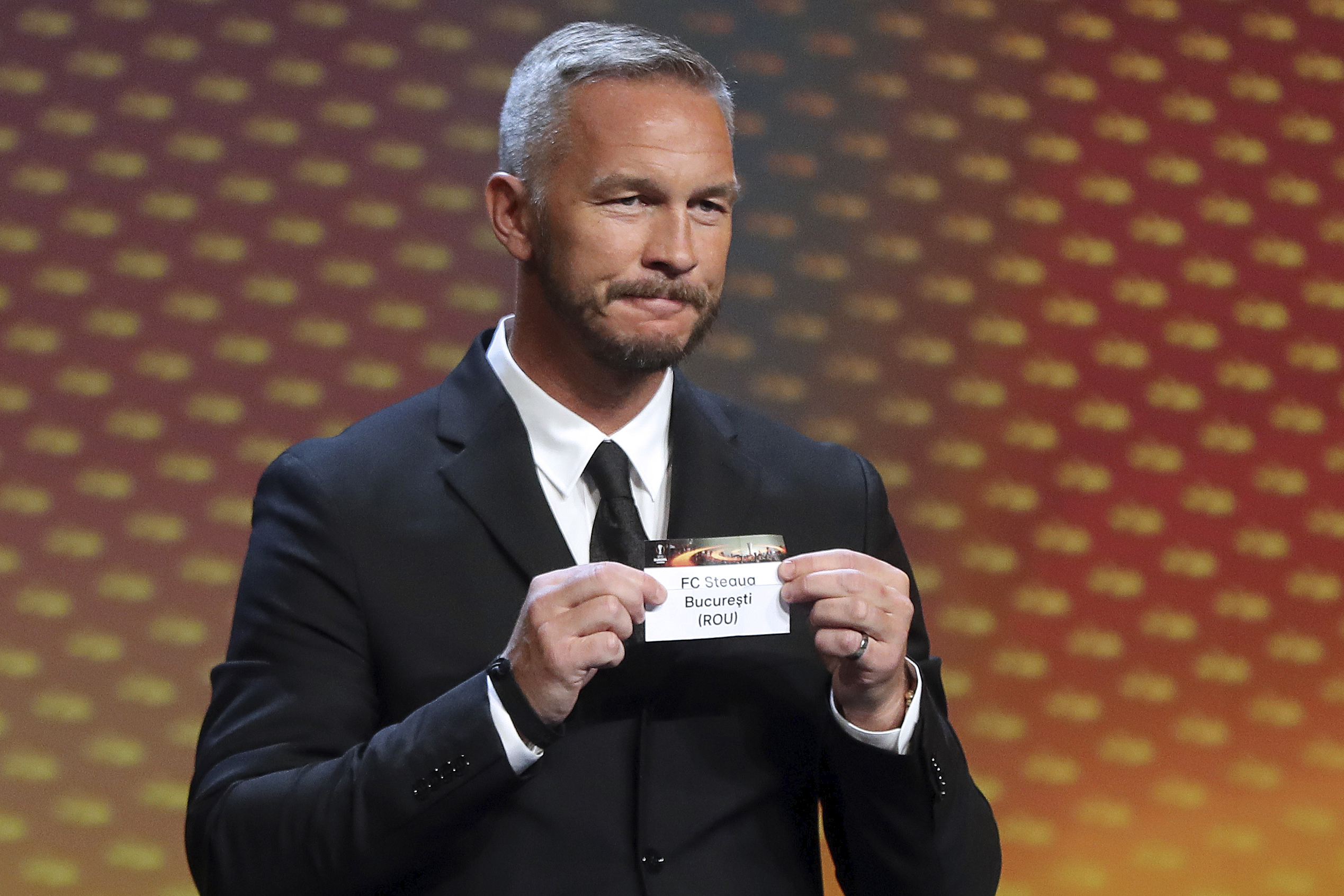 Swedish former football player Patrik Andersson shows a piece of paper bearing the name of FC Steaua Bucuresti, during the UEFA Europa League group stage draw ceremony, on August 26, 2016, in Monaco. / AFP / VALERY HACHE        (Photo credit should read VALERY HACHE/AFP/Getty Images)