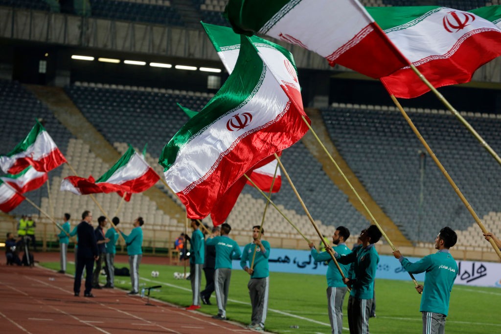 A picture taken on May 19, 2018 shows the Iranian flag being waved at Azadi stadium with fireworks behind during the ceremony bidding farewell to the national team as they head to the 2018 FIFA World Cup finals in Russia, after their international friendly match against Uzbekistan. (Photo by ATTA KENARE / AFP) (Photo credit should read ATTA KENARE/AFP/Getty Images)