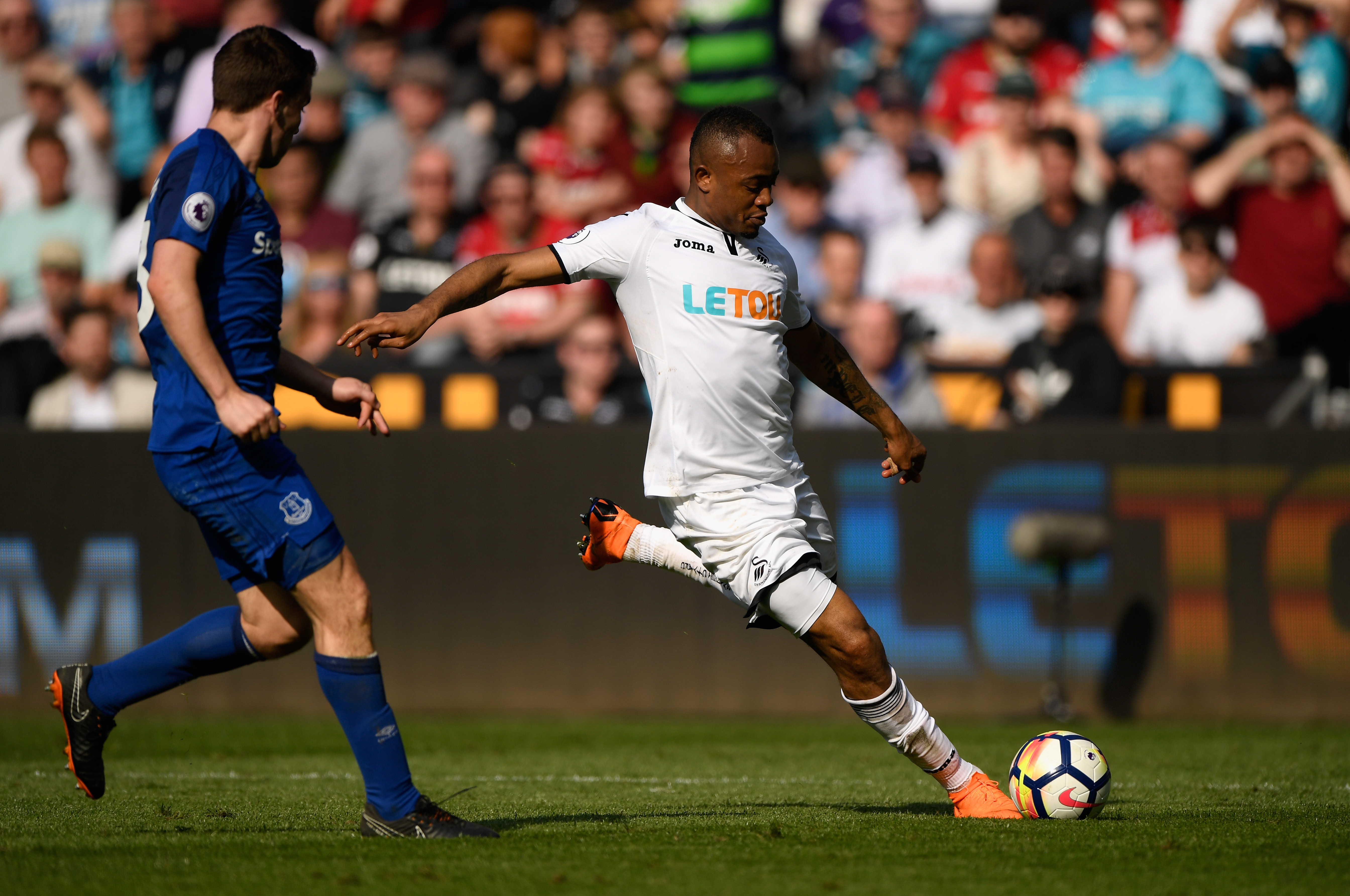 SWANSEA, WALES - APRIL 14:  Swansea player Jordan Ayew shoots at goal despite the challenge of Phil Jagielka during the Premier League match between Swansea City and Everton at Liberty Stadium on April 14, 2018 in Swansea, Wales.  (Photo by Stu Forster/Getty Images)
