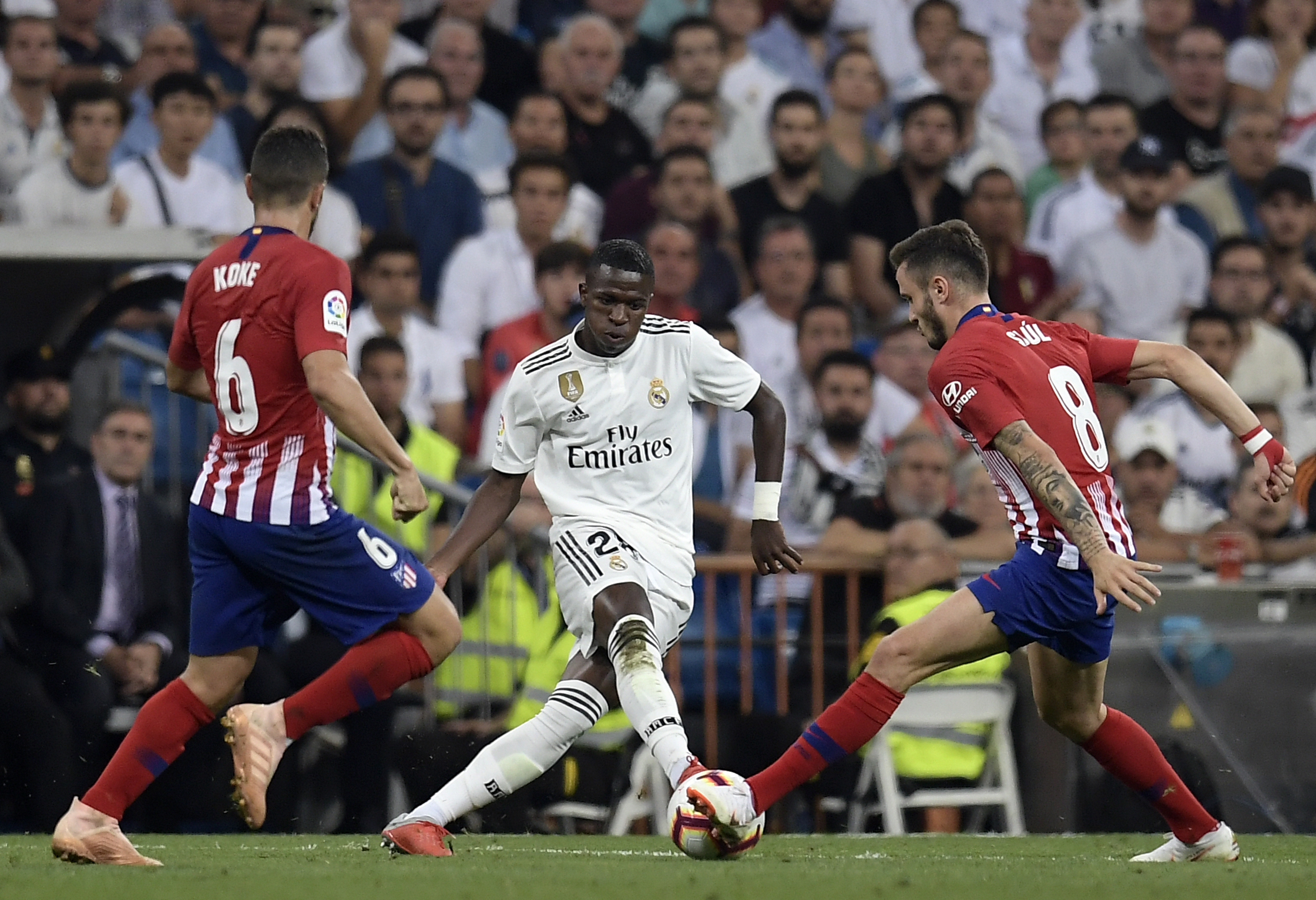 Real Madrid's Brazilian forward Vinicius Juniorv (C) vies with Atletico Madrid's Spanish midfielder Koke (L) and Atletico Madrid's Spanish midfielder Saul Niguez during the Spanish league football match between Real Madrid CF and Club Atletico de Madrid at the Santiago Bernabeu stadium in Madrid on September 29, 2018. (Photo by OSCAR DEL POZO / AFP)        (Photo credit should read OSCAR DEL POZO/AFP/Getty Images)