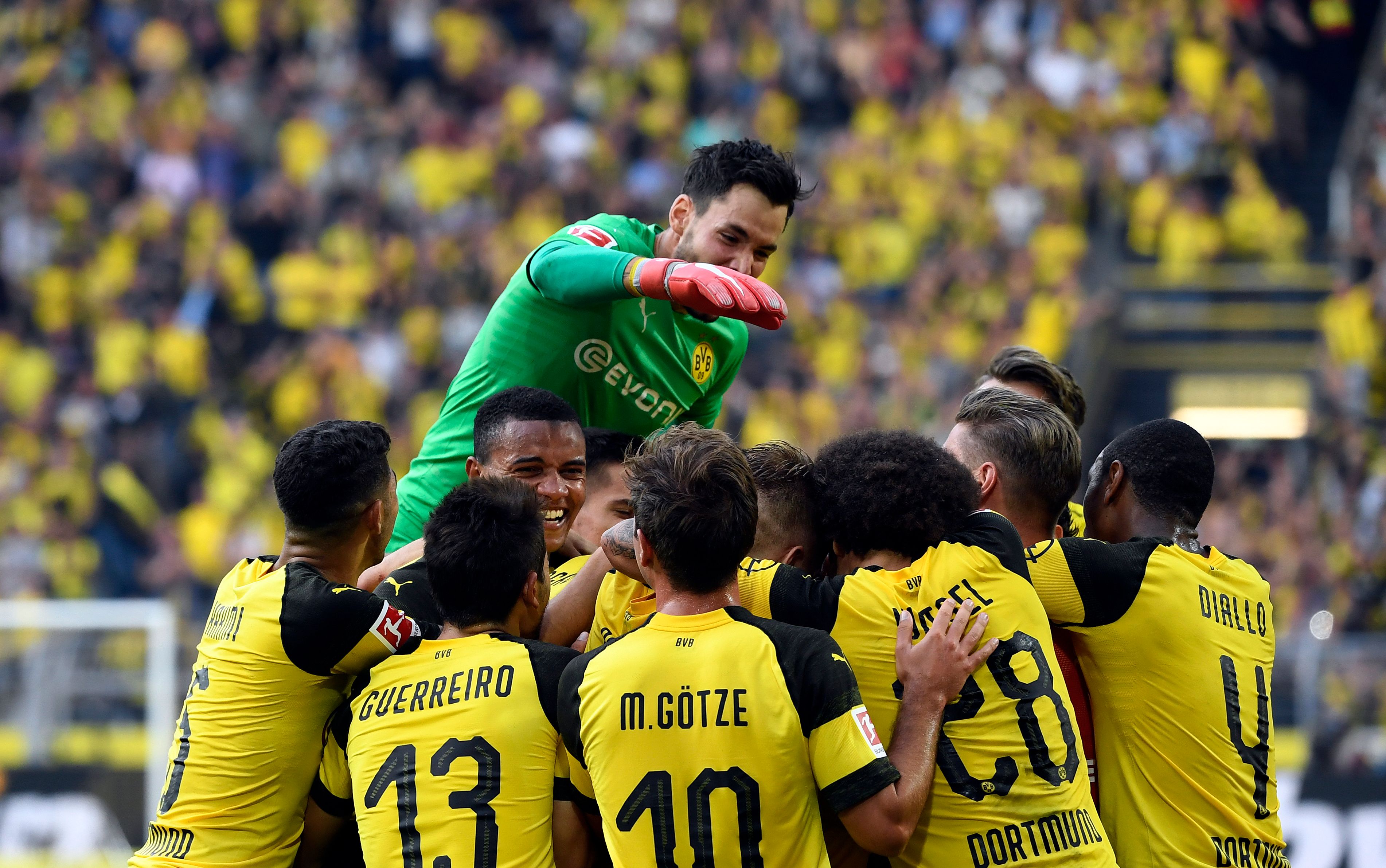 Dortmund's Swiss goalkeeper Roman Buerki (Up) celebrates with team mates the victory over Augsburg during the German first division Bundesliga football match Borussia Dortmund vs FC Augsburg in Dortmund, western Germany, on October 6, 2018. (Photo by INA FASSBENDER / AFP) / RESTRICTIONS: DFL REGULATIONS PROHIBIT ANY USE OF PHOTOGRAPHS AS IMAGE SEQUENCES AND/OR QUASI-VIDEO        (Photo credit should read INA FASSBENDER/AFP/Getty Images)