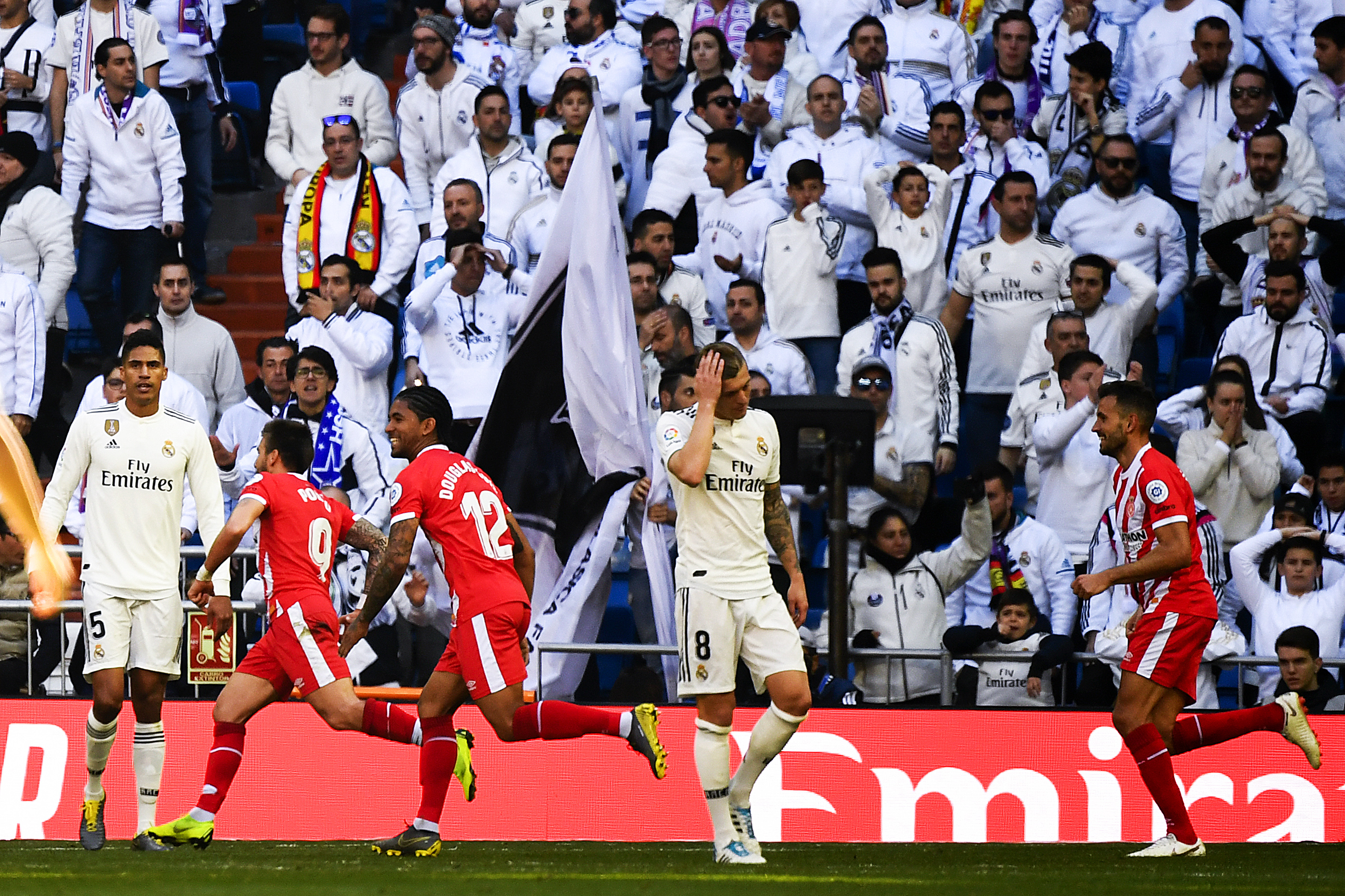 Real Madrid's French defender Raphael Varane (L) and Real Madrid's German midfielder Toni Kroos (C) react as Girona's Spanish midfielder Portu (2ndL) celebrates with teammates after scoring his team's second goal during the Spanish League football match between Real Madrid and Girona at the Santiago Bernabeu stadium in Madrid on February 17, 2019. (Photo by GABRIEL BOUYS / AFP)        (Photo credit should read GABRIEL BOUYS/AFP/Getty Images)