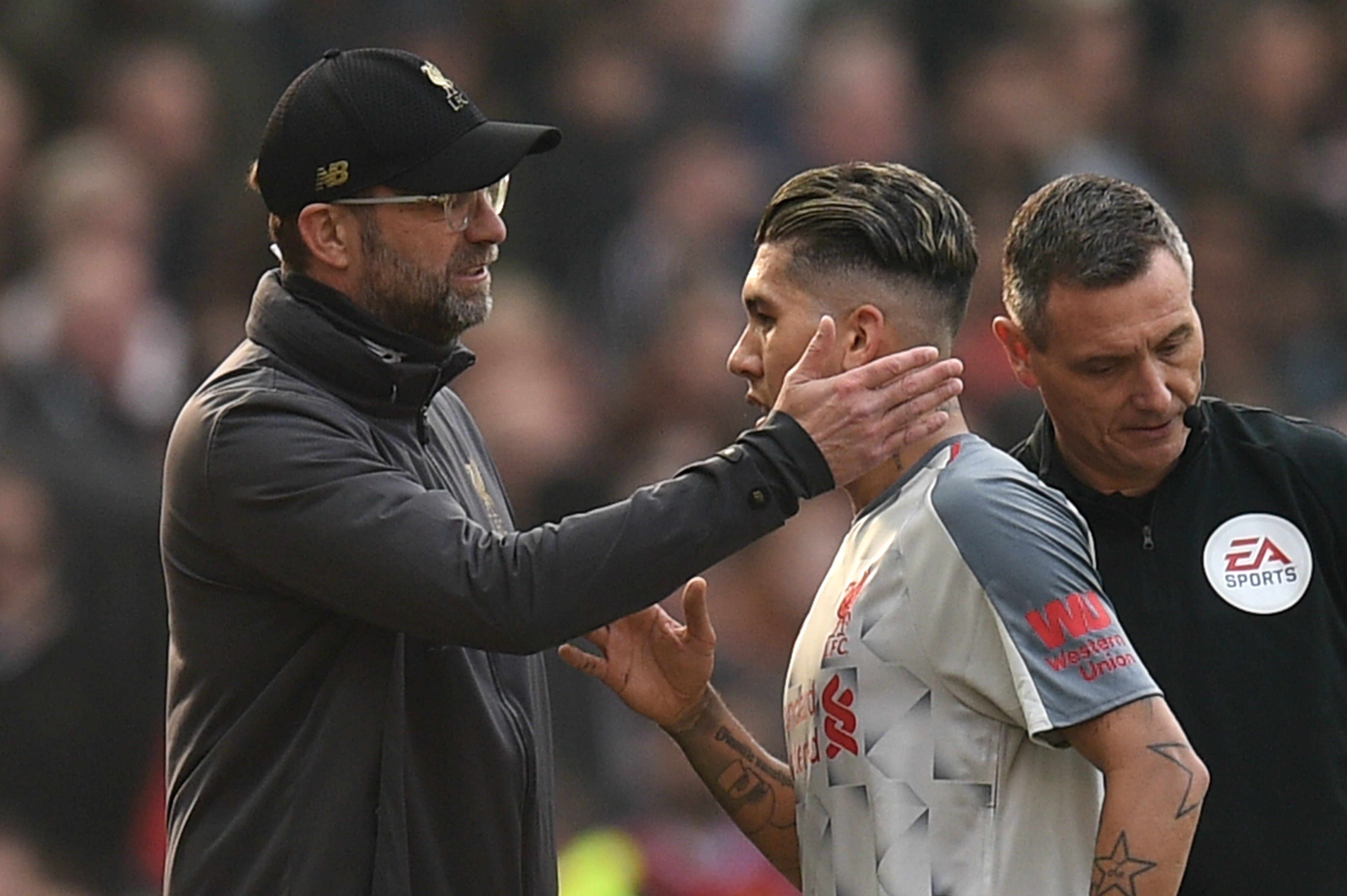 Liverpool's German manager Jurgen Klopp (L) greets Liverpool's Brazilian midfielder Roberto Firmino (R) as he leaves the pitch substituted with an injury during the English Premier League football match between Manchester United and Liverpool at Old Trafford in Manchester, north west England, on February 24, 2019. (Photo by Oli SCARFF / AFP) / RESTRICTED TO EDITORIAL USE. No use with unauthorized audio, video, data, fixture lists, club/league logos or 'live' services. Online in-match use limited to 120 images. An additional 40 images may be used in extra time. No video emulation. Social media in-match use limited to 120 images. An additional 40 images may be used in extra time. No use in betting publications, games or single club/league/player publications. /         (Photo credit should read OLI SCARFF/AFP/Getty Images)