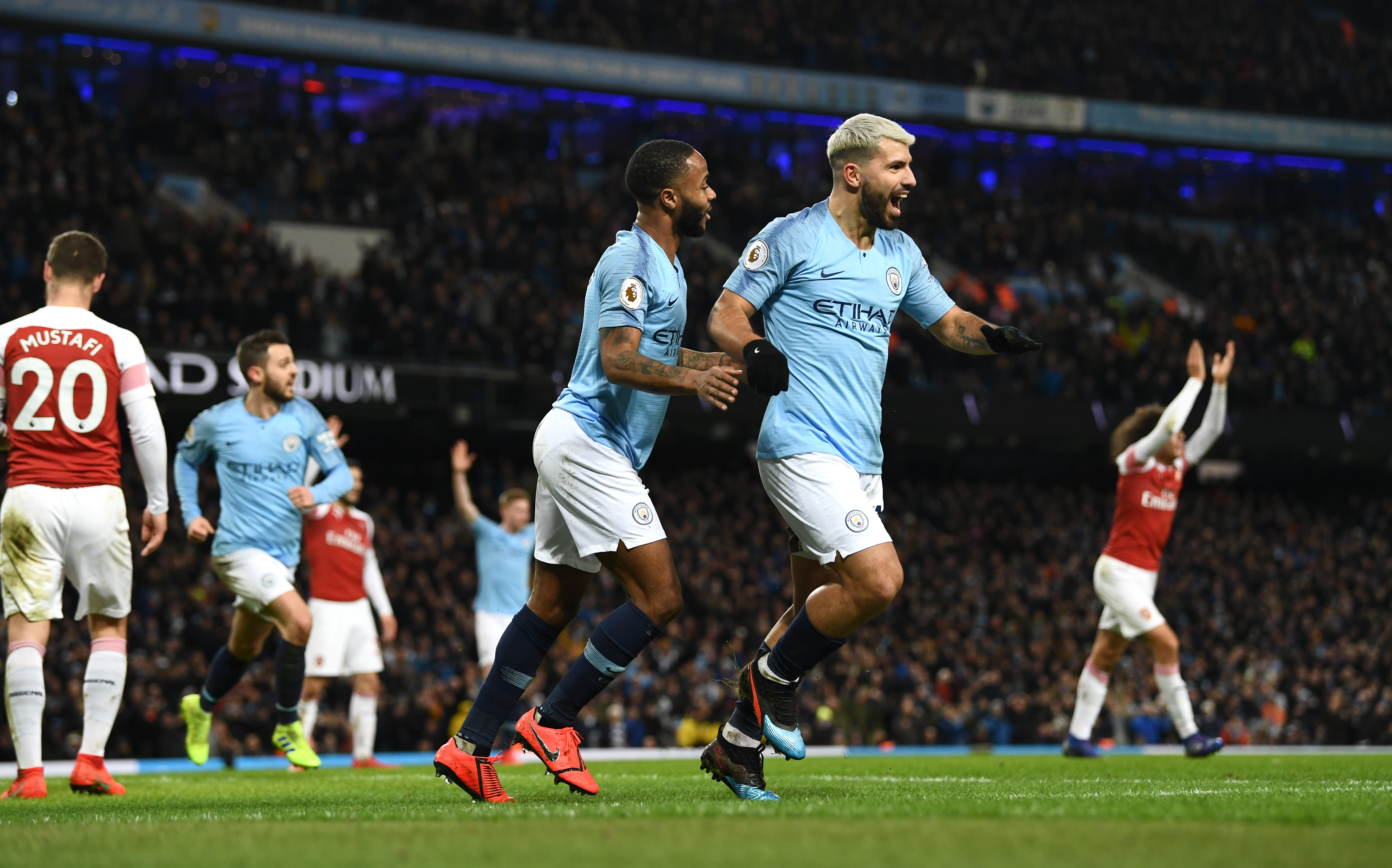 MANCHESTER, ENGLAND - FEBRUARY 03: Manchester City striker Sergio Aguero (r) celebrates with Raheem Sterling after scoring his hat trick goal despite the efforts of Arsenal goalkeeper Bernd Leno and Laurent Koscielny during the Premier League match between Manchester City and Arsenal FC at Etihad Stadium on February 03, 2019 in Manchester, United Kingdom. (Photo by Stu Forster/Getty Images)