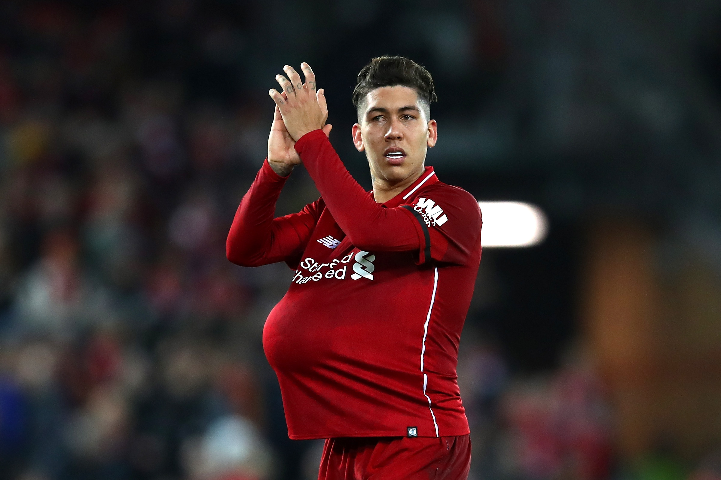 LIVERPOOL, ENGLAND - DECEMBER 29:  Roberto Firmino of Liverpool hides the match ball under his shirt after scoring a hat-trick during the Premier League match between Liverpool FC and Arsenal FC at Anfield on December 29, 2018 in Liverpool, United Kingdom.  (Photo by Clive Brunskill/Getty Images)