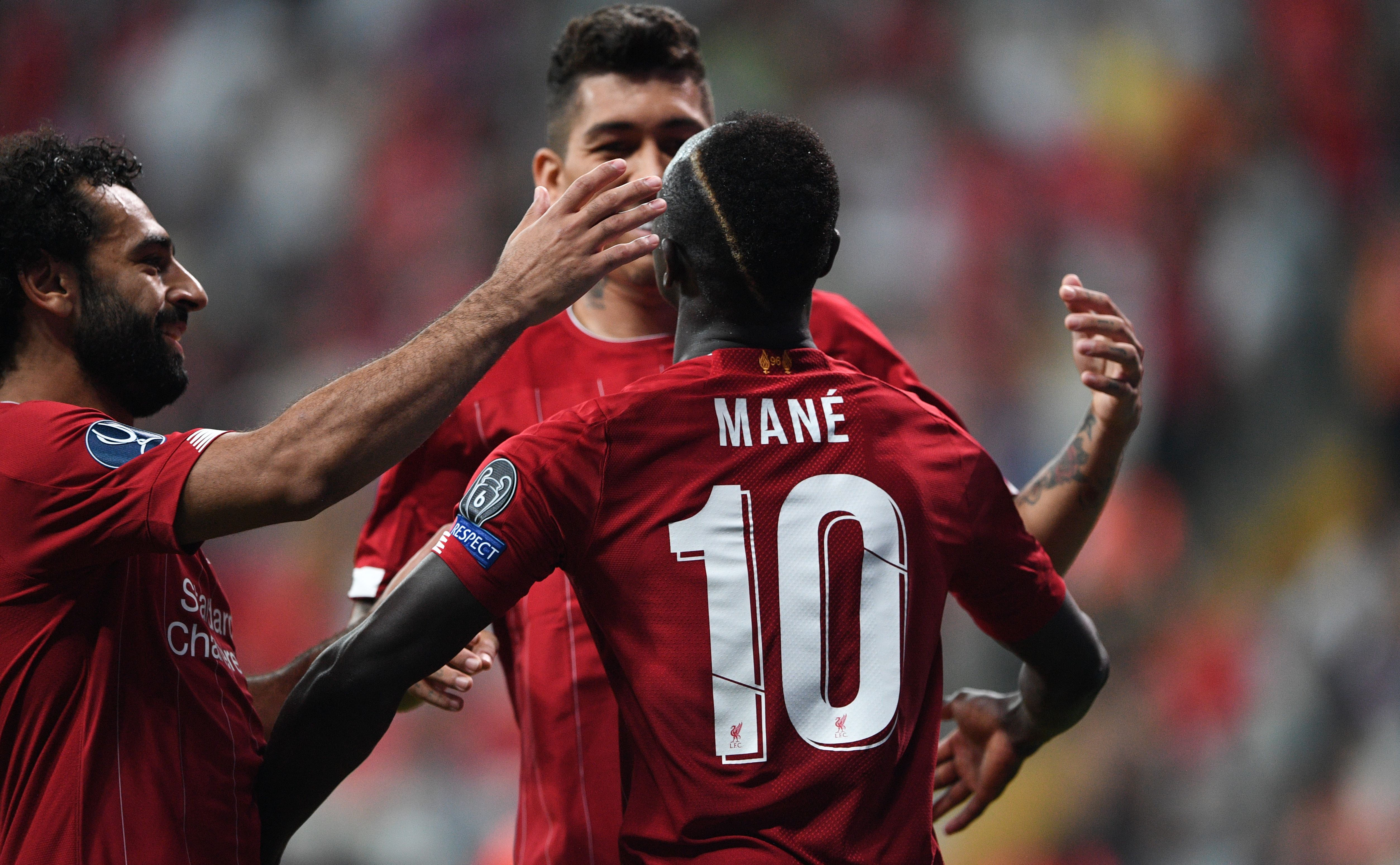 Liverpool's Senegalese striker Sadio Mane (R) celebrates with teammates Liverpool's Egyptian midfielder Mohamed Salah (L) and Liverpool's Brazilian midfielder Roberto Firmino after scoring a goal during the UEFA Super Cup 2019 football match between FC Liverpool and FC Chelsea at Besiktas Park Stadium in Istanbul on August 14, 2019. (Photo by Bulent Kilic / AFP)        (Photo credit should read BULENT KILIC/AFP/Getty Images)