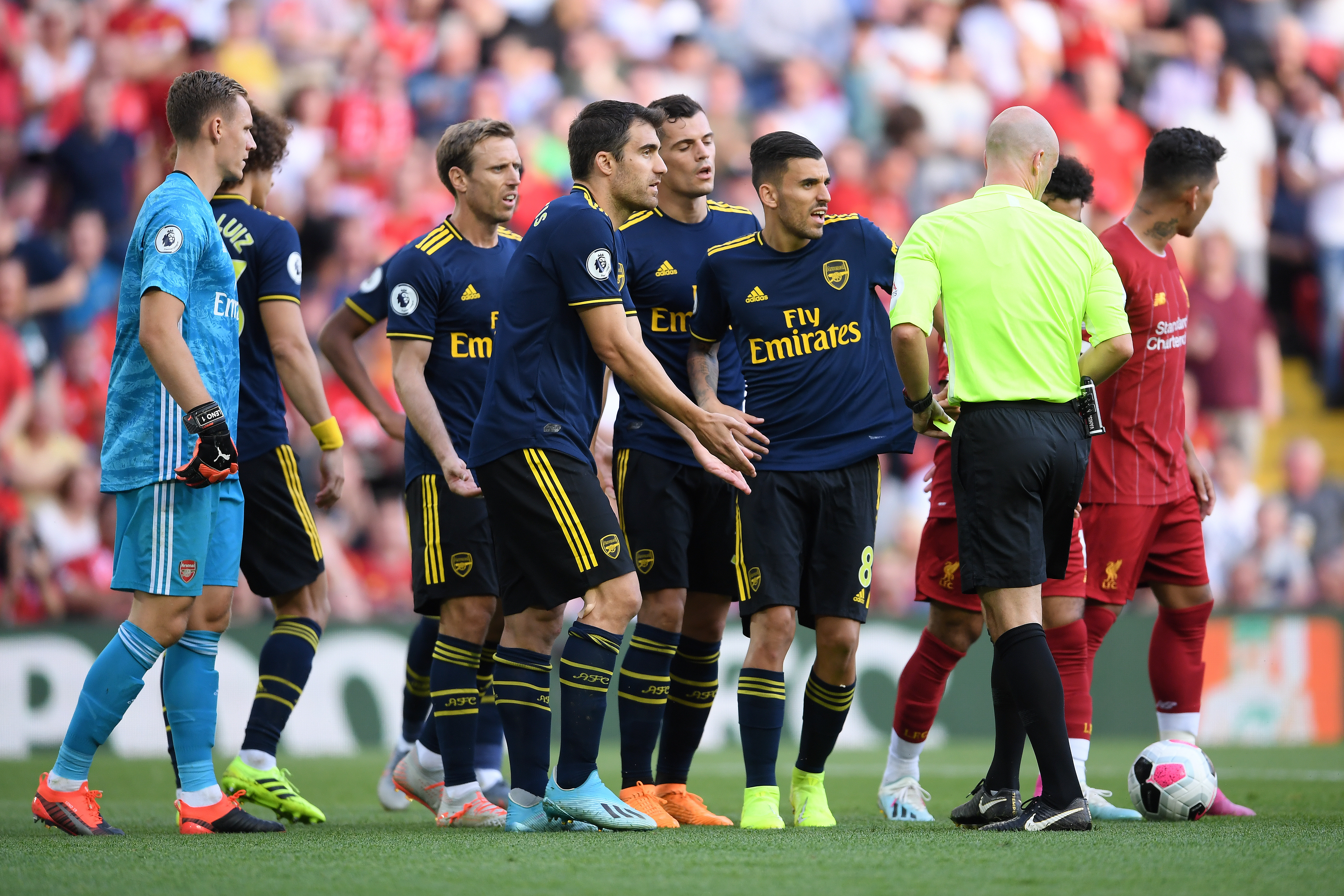 LIVERPOOL, ENGLAND - AUGUST 24: Arsenal players argue with the referee over David Luiz' yellow card during the Premier League match between Liverpool FC and Arsenal FC at Anfield on August 24, 2019 in Liverpool, United Kingdom. (Photo by Laurence Griffiths/Getty Images)