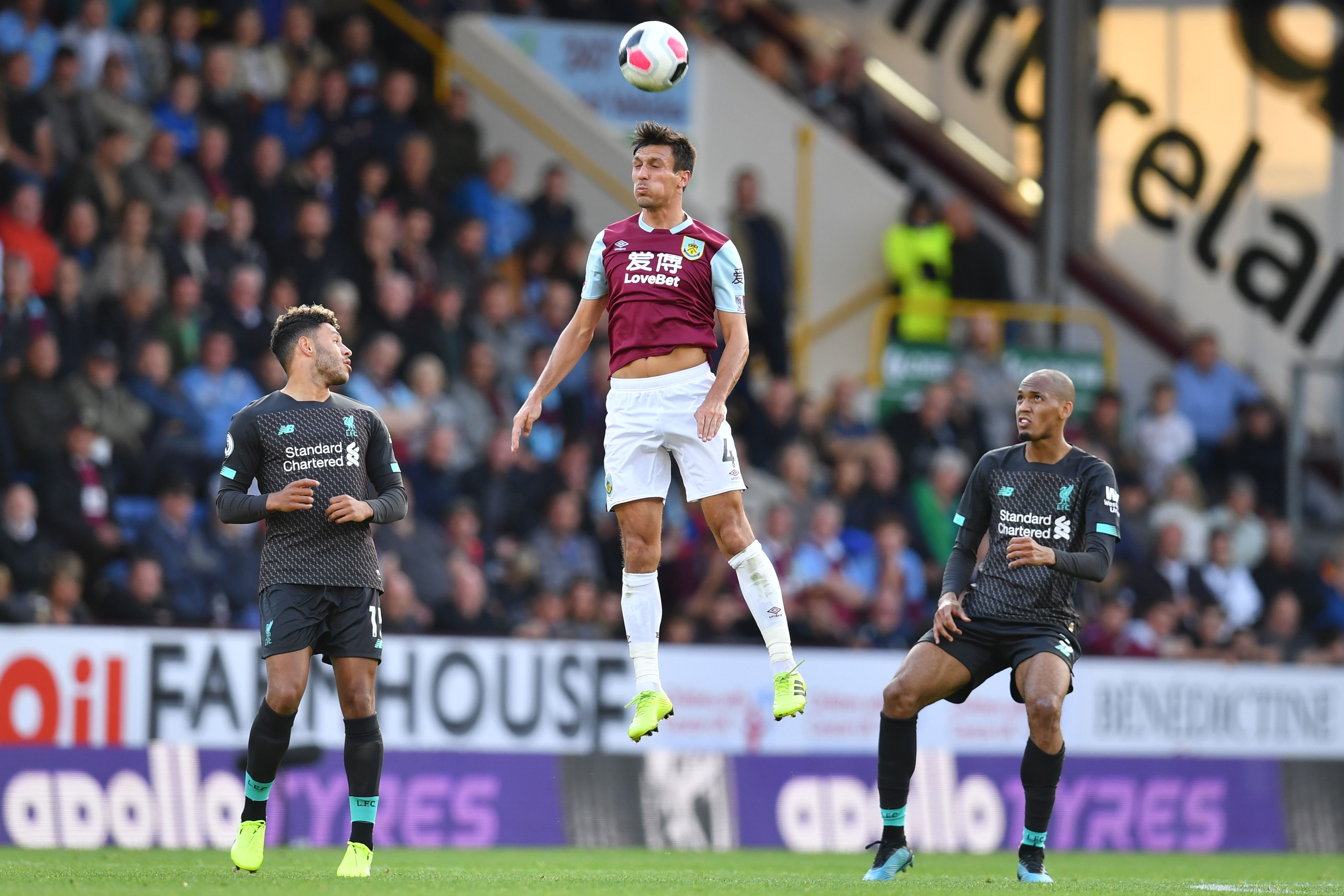 Burnley's English midfielder Jack Cork (C) wins a header as Liverpool's English midfielder Alex Oxlade-Chamberlain (L) and Liverpool's Brazilian midfielder Fabinho (R) look on during the English Premier League football match between Burnley and Liverpool at Turf Moor in Burnley, north west England on August 31, 2019. (Photo by Paul ELLIS / AFP) / RESTRICTED TO EDITORIAL USE. No use with unauthorized audio, video, data, fixture lists, club/league logos or 'live' services. Online in-match use limited to 120 images. An additional 40 images may be used in extra time. No video emulation. Social media in-match use limited to 120 images. An additional 40 images may be used in extra time. No use in betting publications, games or single club/league/player publications. /         (Photo credit should read PAUL ELLIS/AFP via Getty Images)