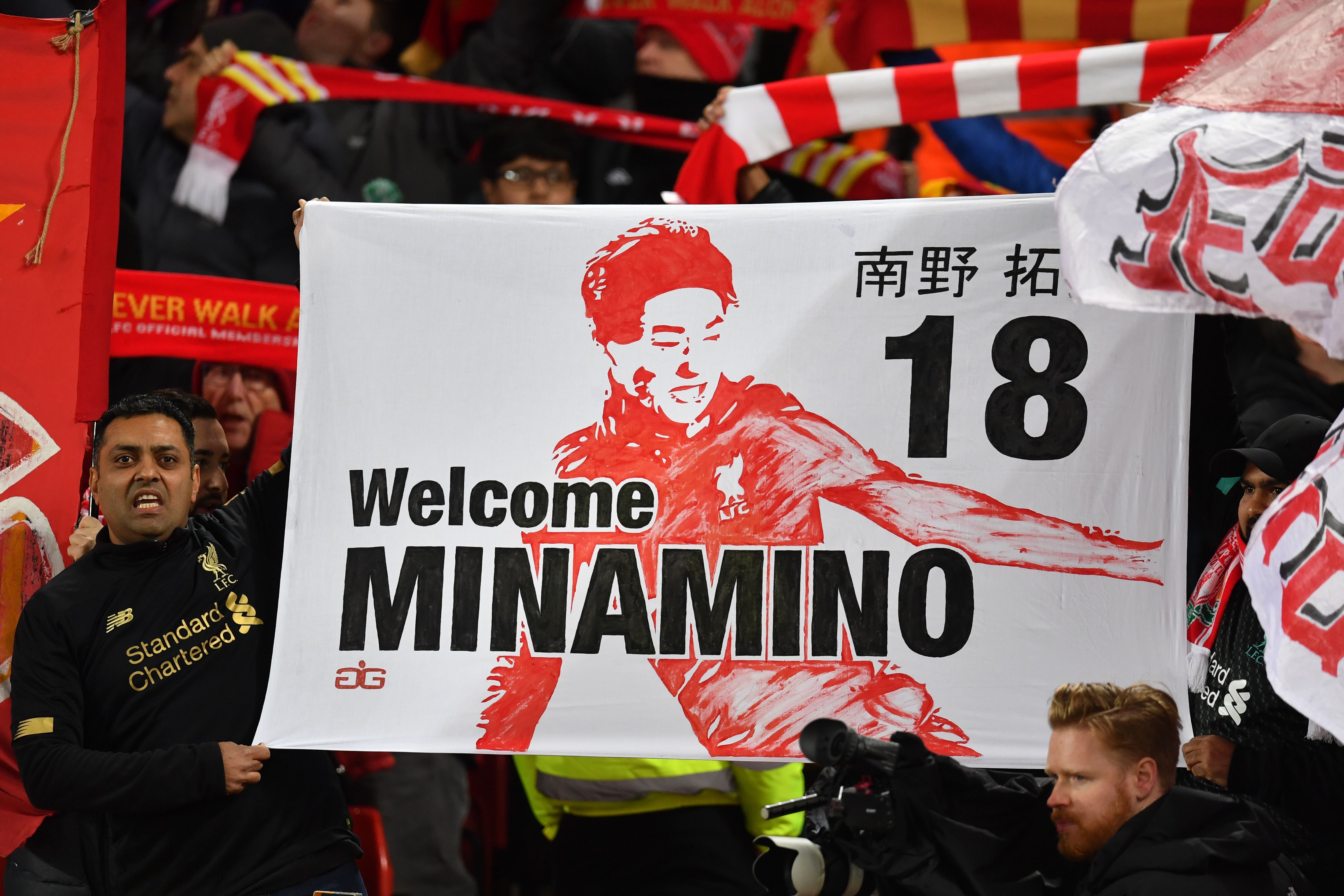 Supporters hold a banner for Liverpool's new signing, Japanese midfielder Takumi Minamino during the English Premier League football match between Liverpool and Sheffield United at Anfield in Liverpool, north west England on January 2, 2020. (Photo by Paul ELLIS / AFP) / RESTRICTED TO EDITORIAL USE. No use with unauthorized audio, video, data, fixture lists, club/league logos or 'live' services. Online in-match use limited to 120 images. An additional 40 images may be used in extra time. No video emulation. Social media in-match use limited to 120 images. An additional 40 images may be used in extra time. No use in betting publications, games or single club/league/player publications. /  (Photo by Paul Ellis/AFP via Getty Images)