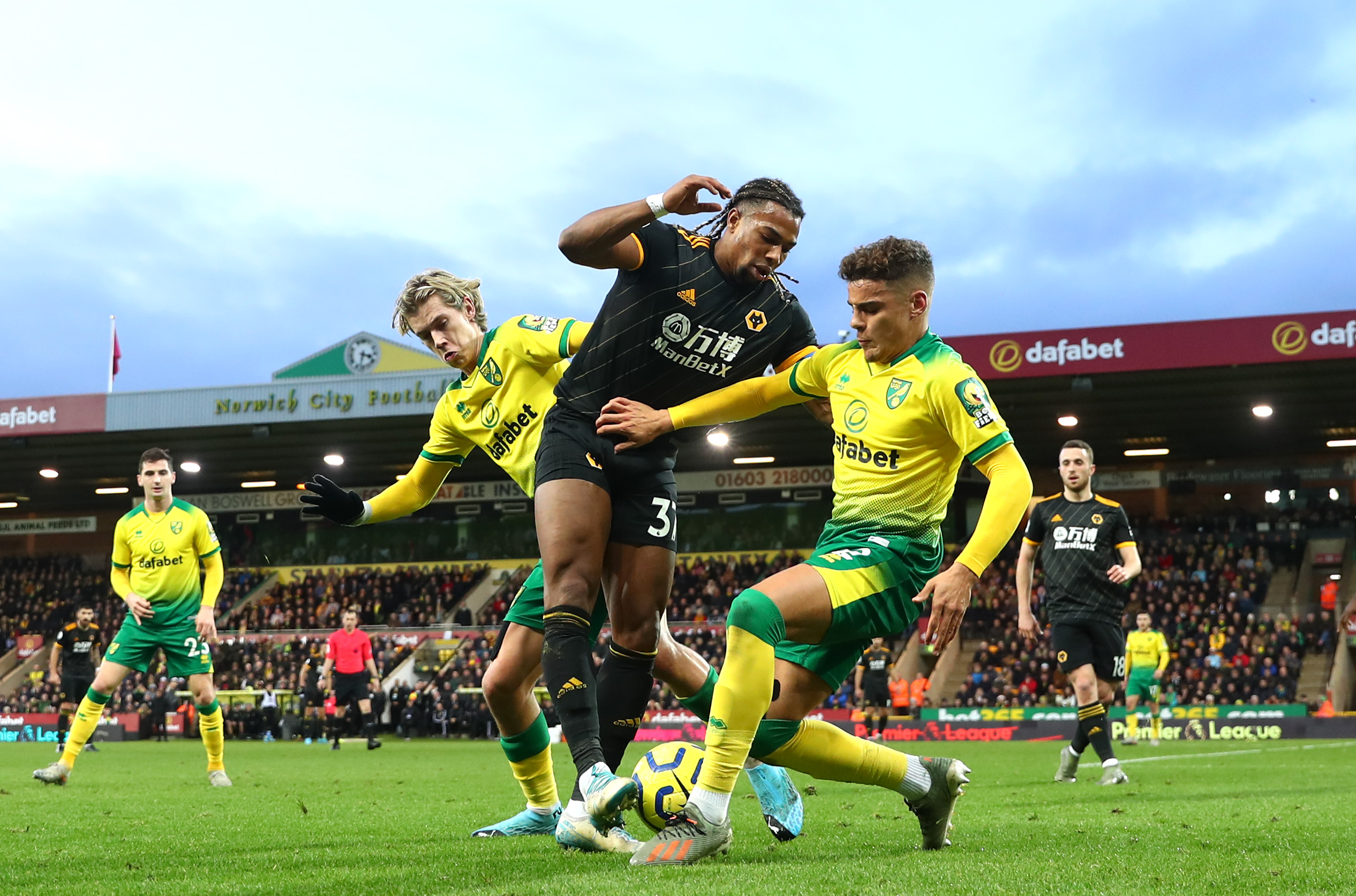 NORWICH, ENGLAND - DECEMBER 21: Adama Traore of Wolverhampton Wanderers is tackled by Todd Cantwell and Max Aarons of Norwich City during the Premier League match between Norwich City and Wolverhampton Wanderers at Carrow Road on December 21, 2019 in Norwich, United Kingdom. (Photo by Julian Finney/Getty Images)